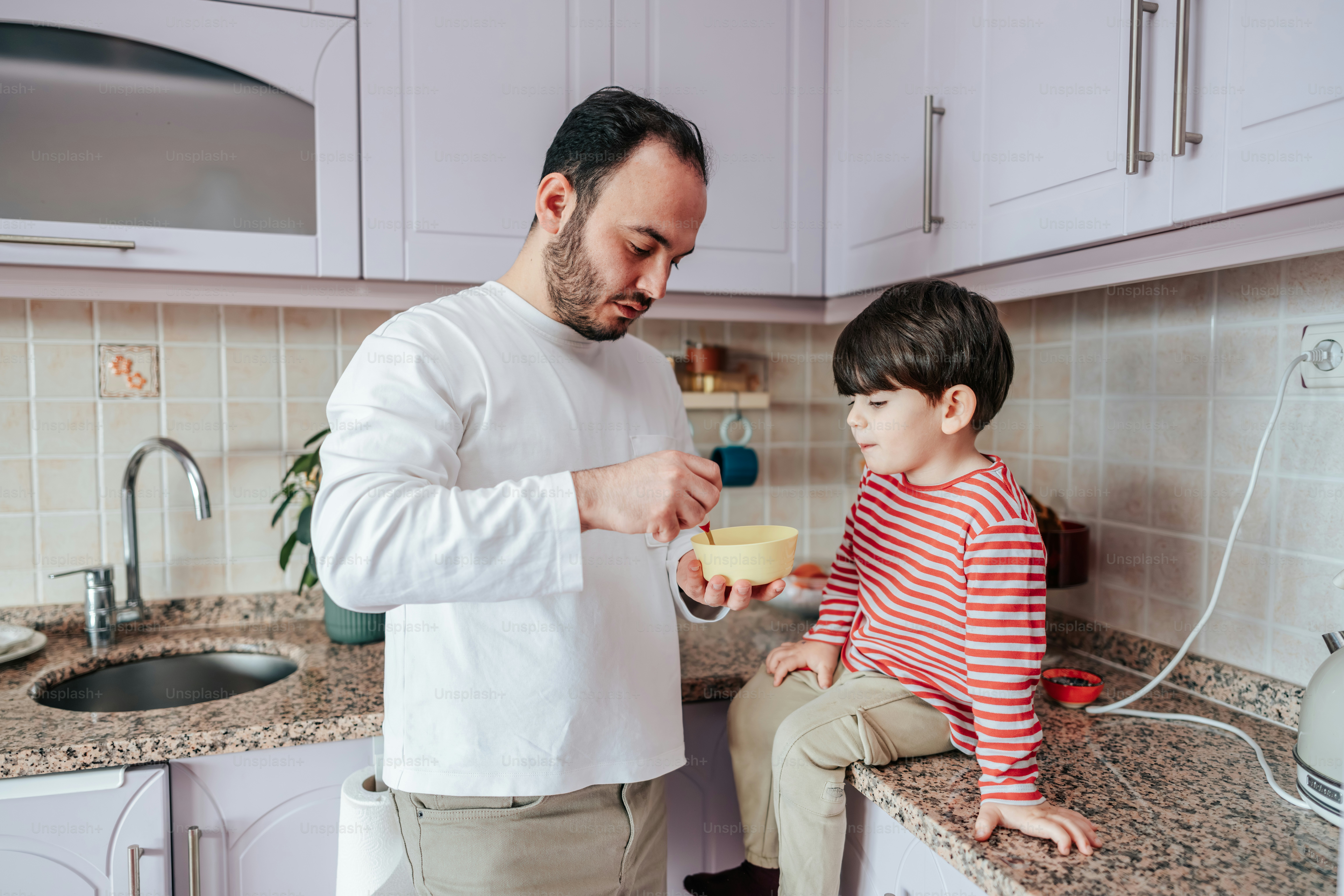 Ayah memberi makan sereal kepada putranya di dapur.
