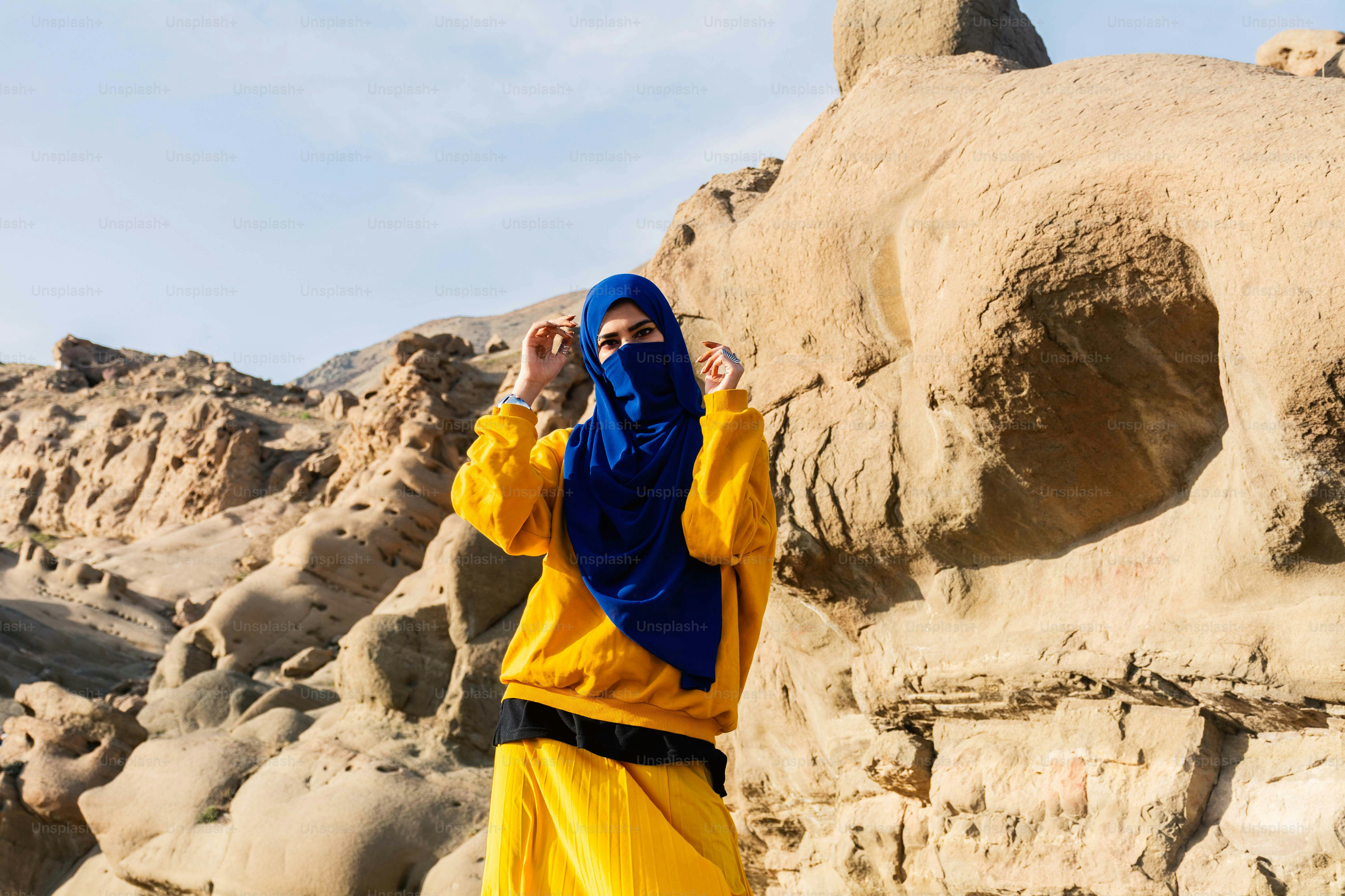 Femme en hijab pose dans un paysage désertique rocheux