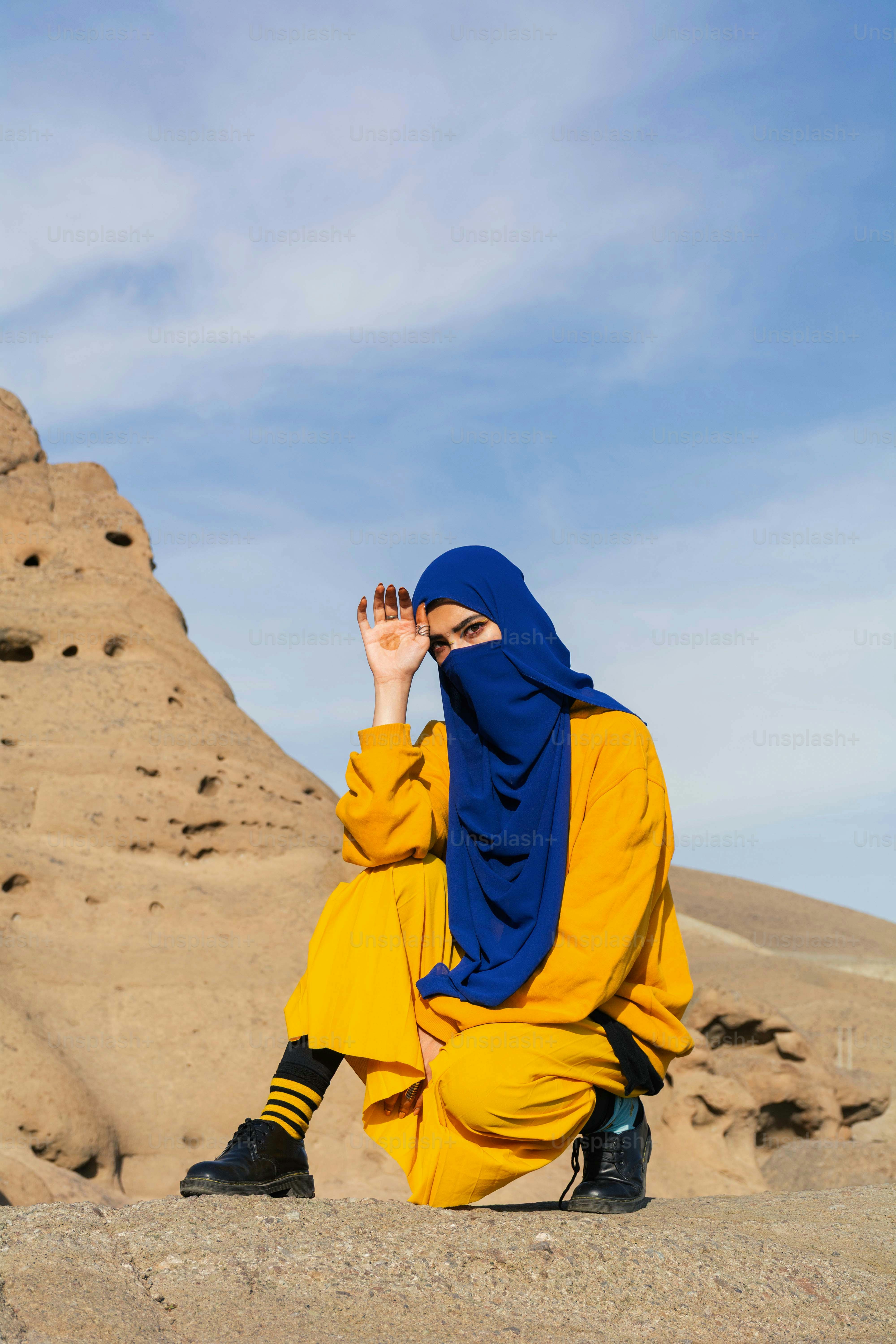 Femme en tenue jaune et hijab bleu dans le désert