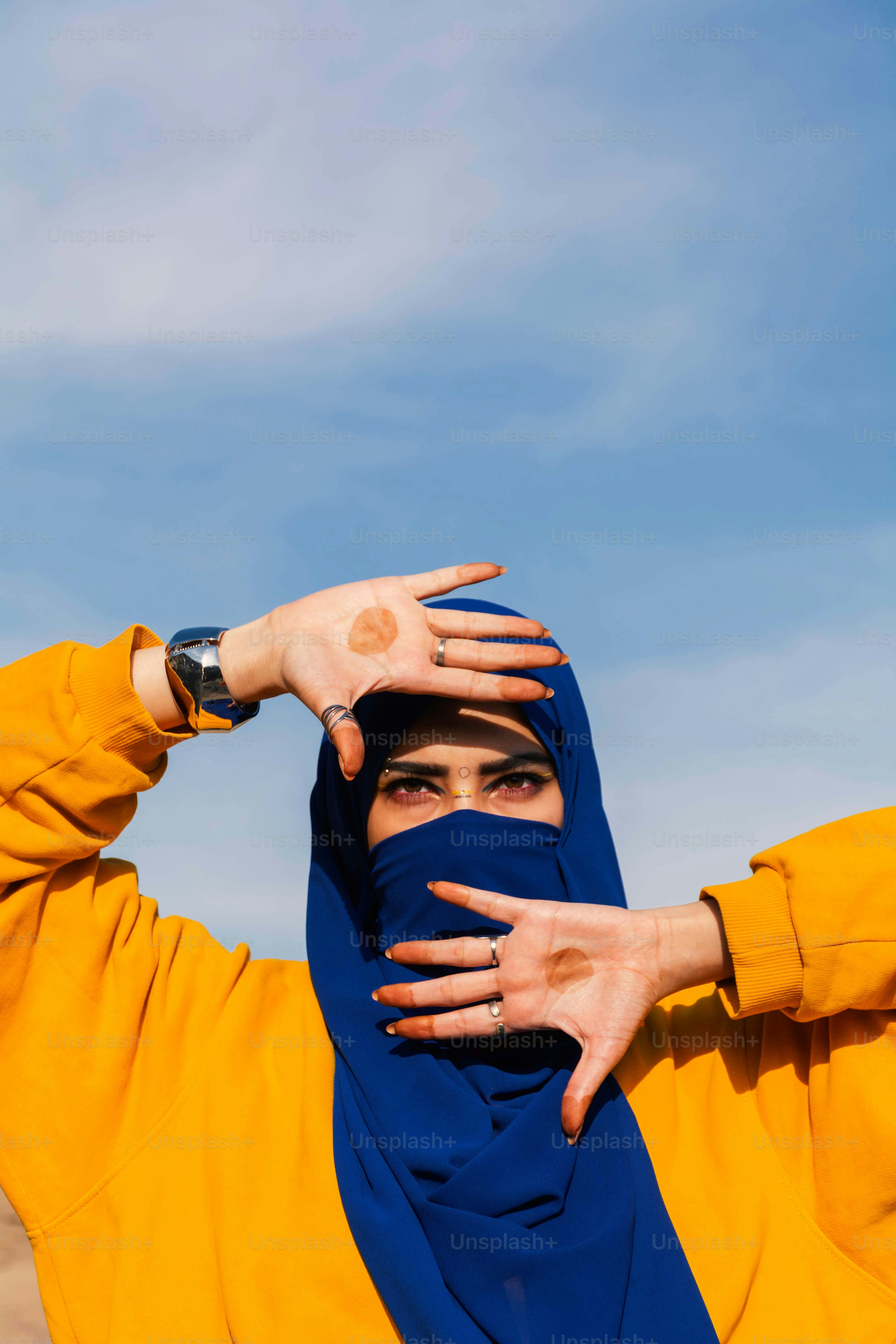 Femme en hijab bleu et sweat jaune encadre le visage