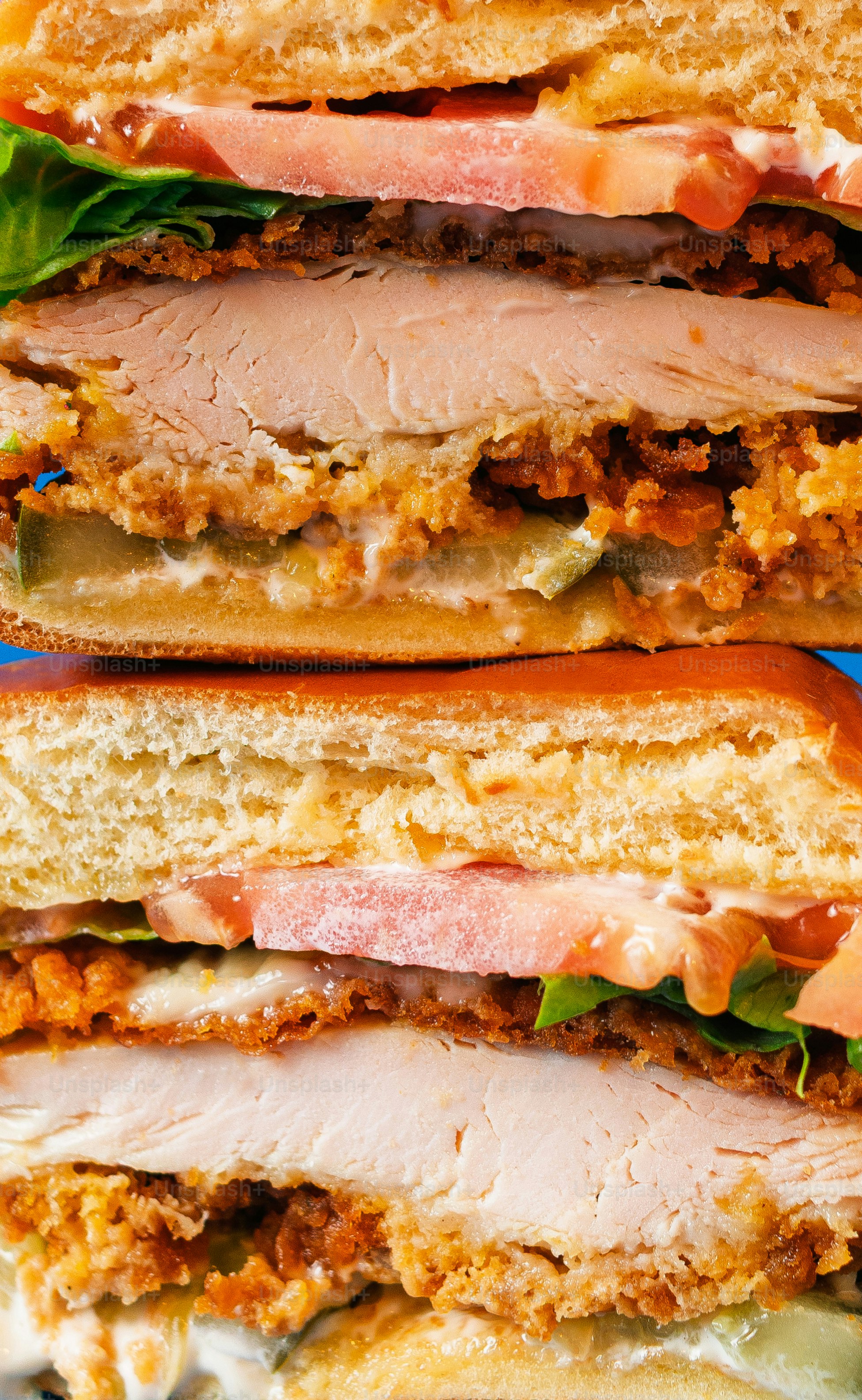 Un grand sandwich empilé de poulet frit et de légumes.