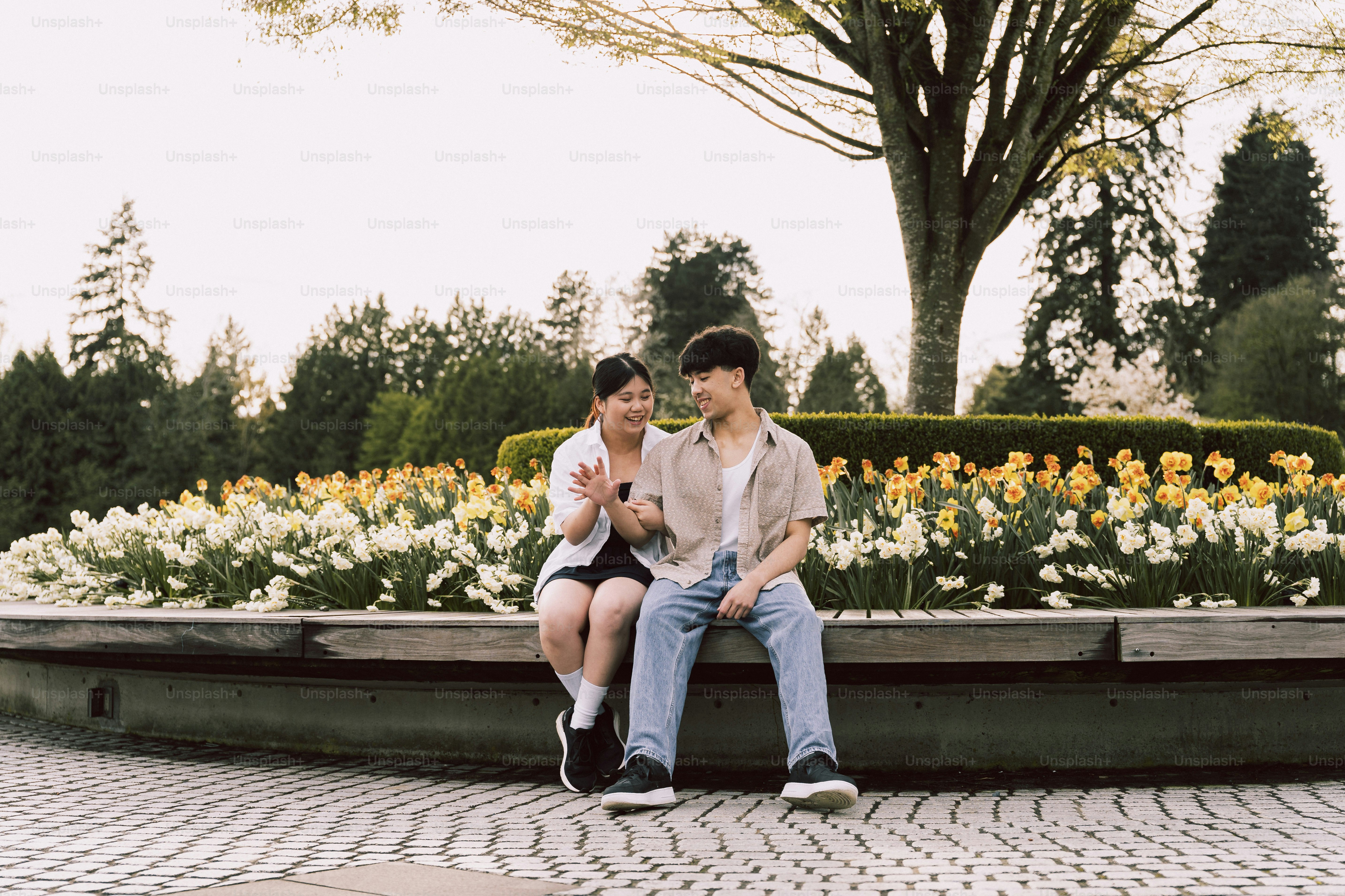 Un couple est assis sur un banc entouré de fleurs.
