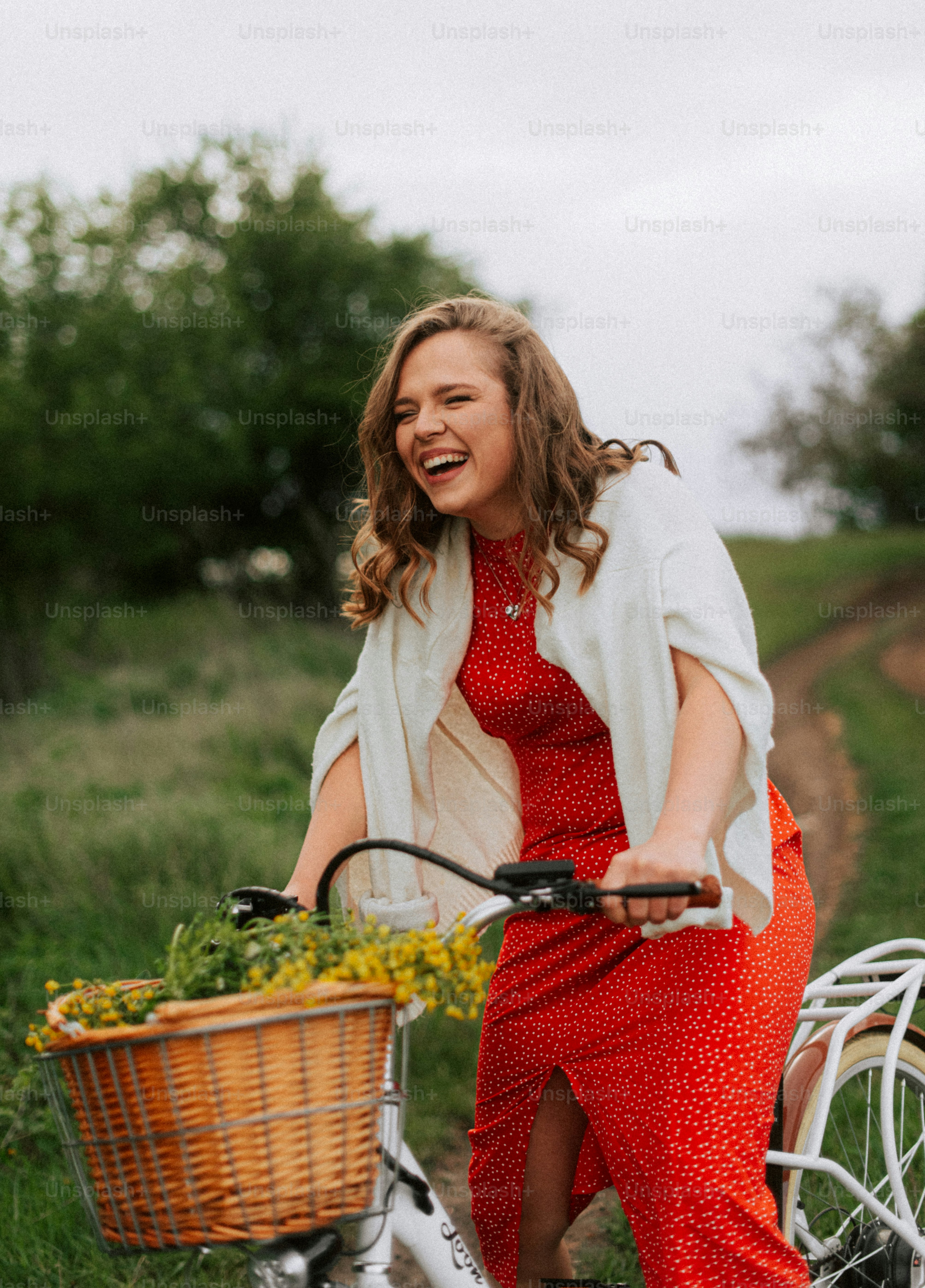 A woman in a red dress rides a bicycle outdoors.