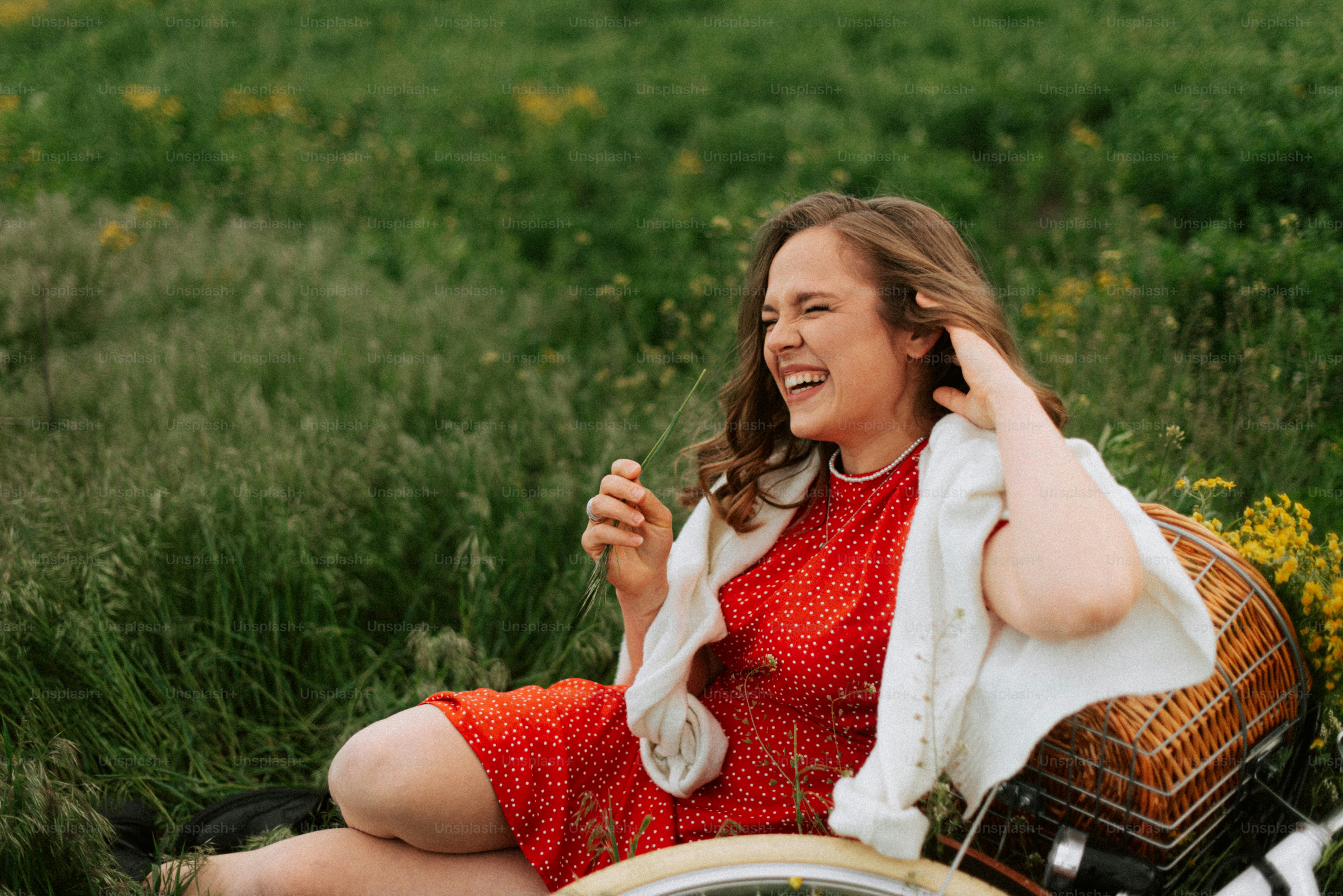 Woman laughing in a field with a bicycle