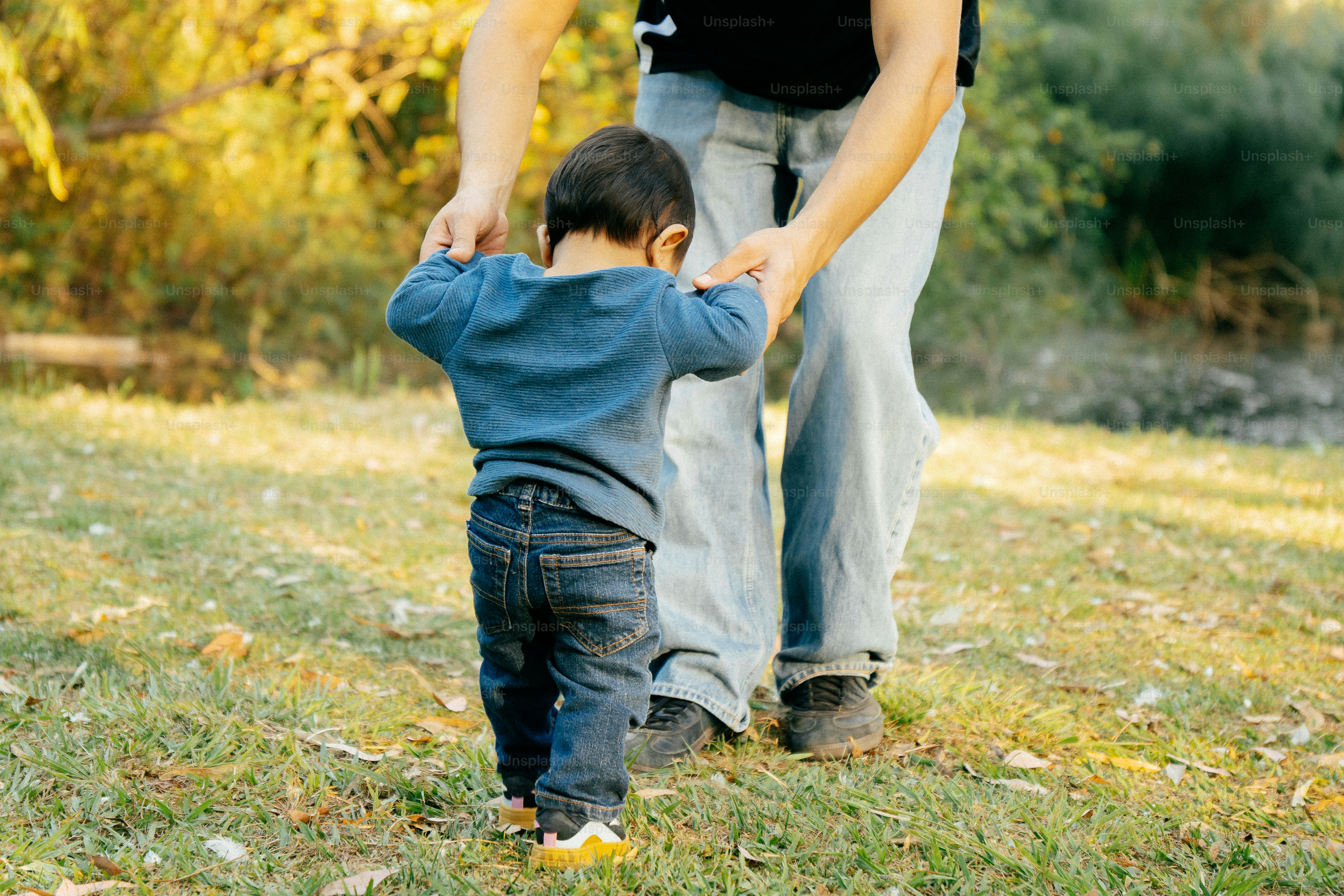 Un adulte aide l’enfant à faire ses premiers pas en plein air