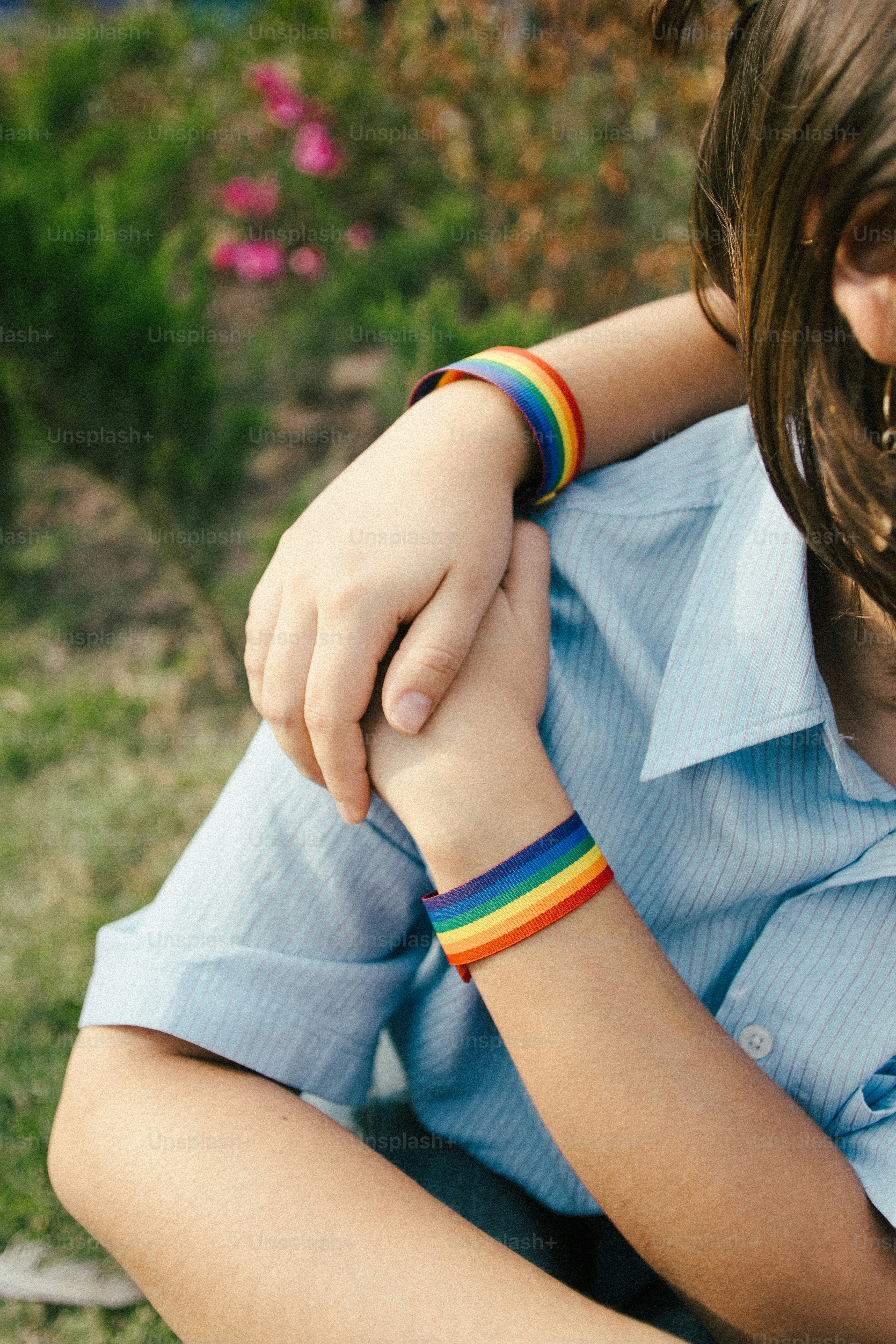 Deux personnes portant des bracelets arc-en-ciel