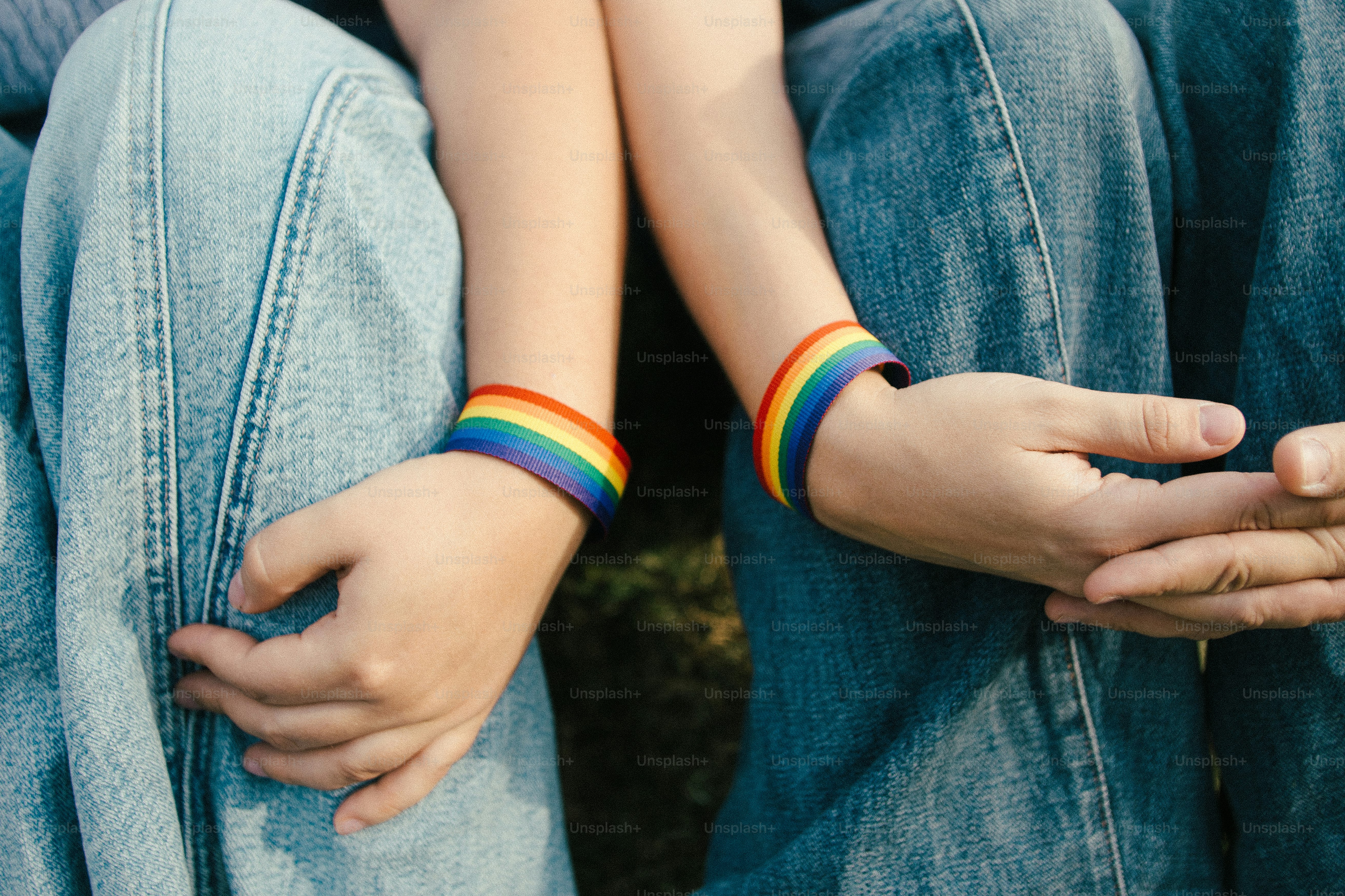 Deux personnes portant des bracelets arc-en-ciel assises ensemble