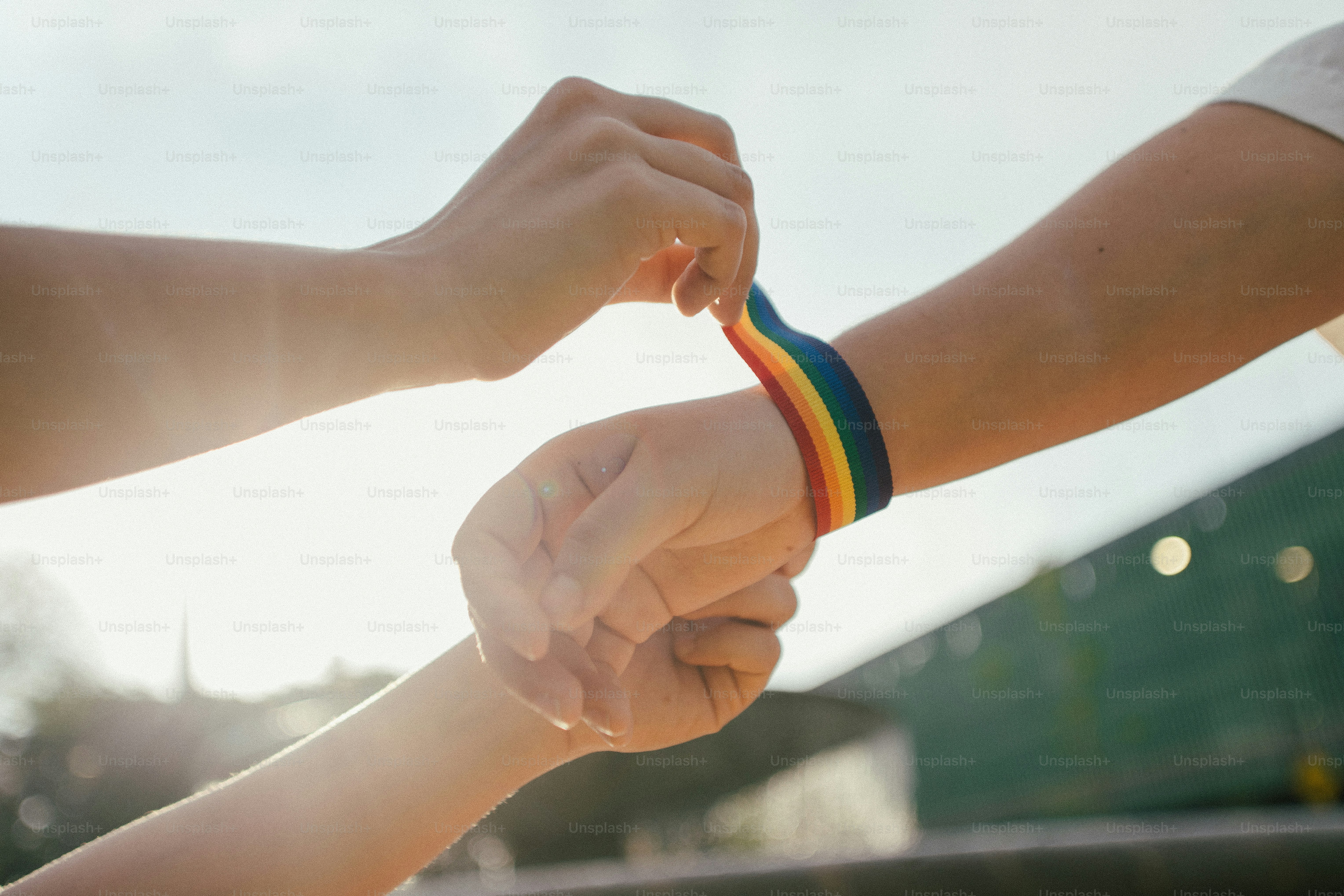 Quelqu’un met un bracelet arc-en-ciel sur le bras d’une autre personne.