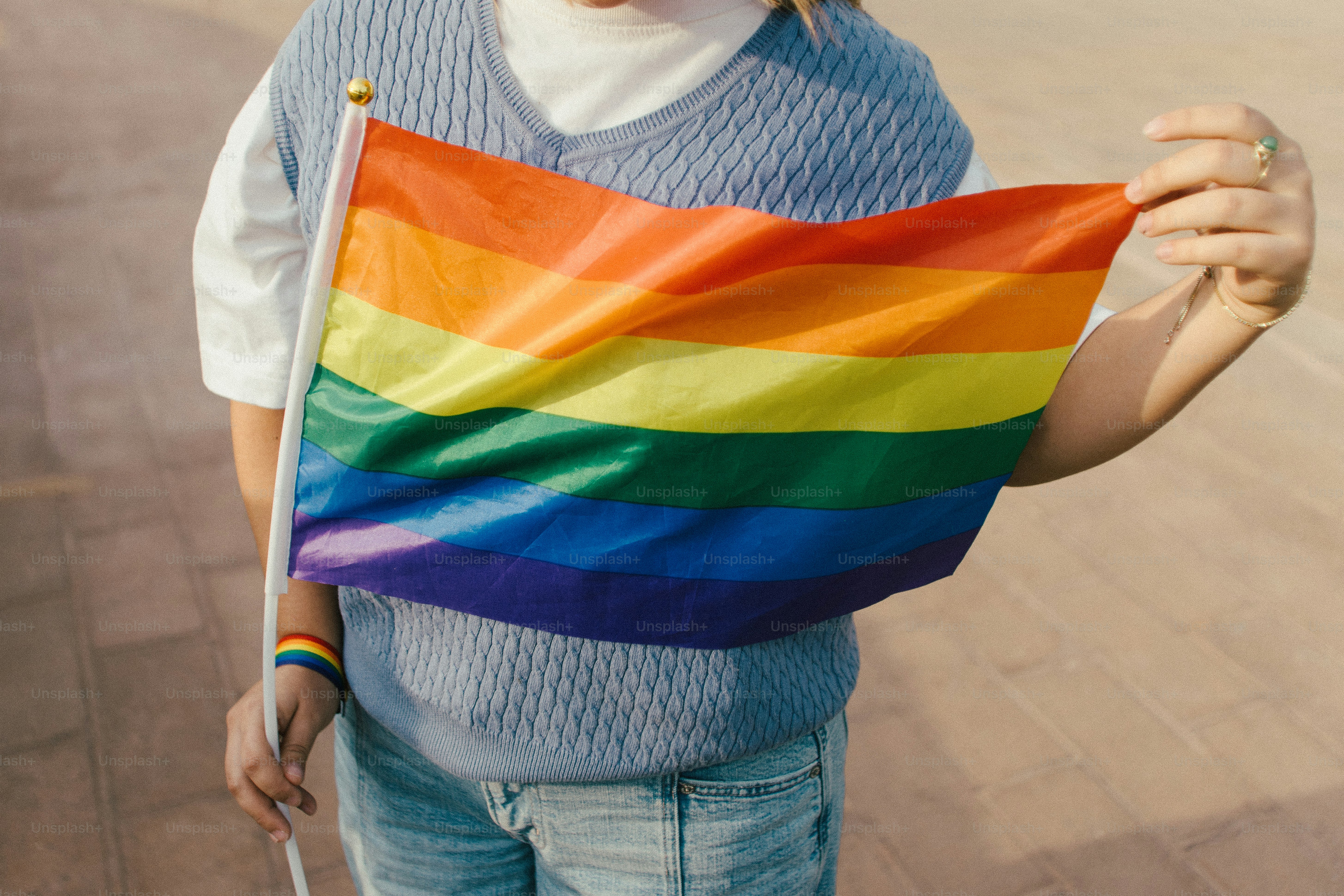 Personne tenant un drapeau arc-en-ciel de la fierté