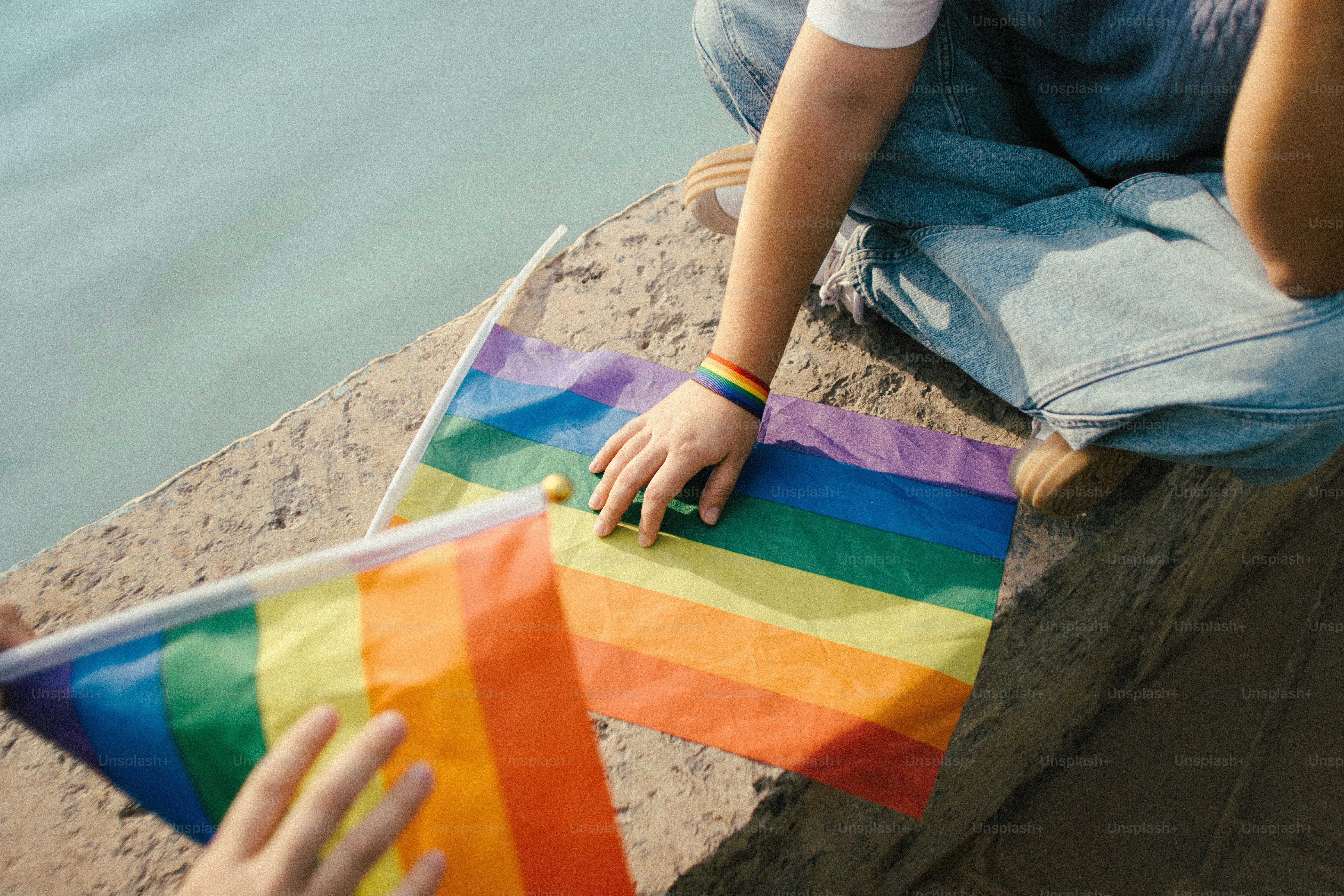 Mains tenant des drapeaux arc-en-ciel près de l’eau