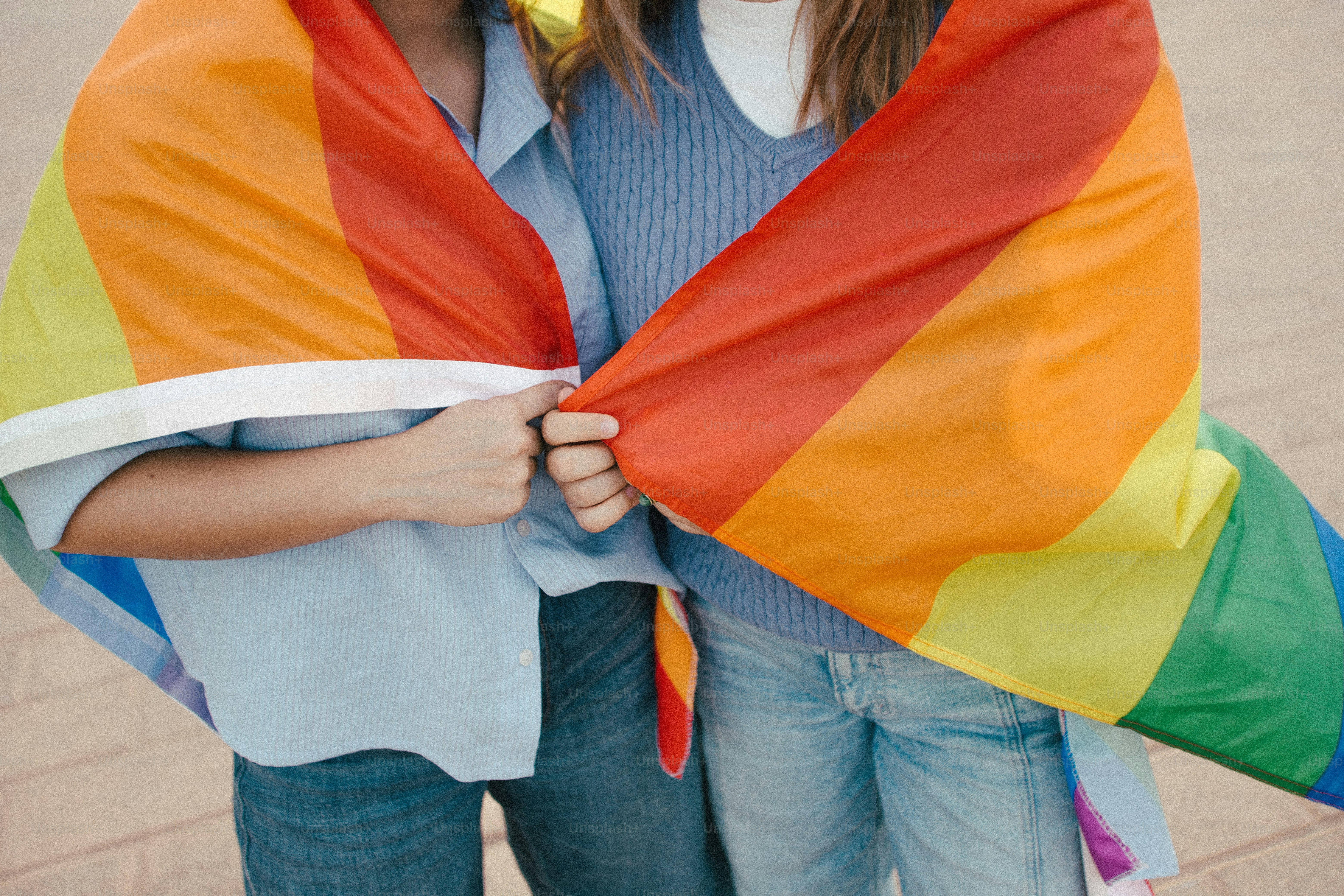 Deux personnes enveloppées dans un drapeau arc-en-ciel de la fierté
