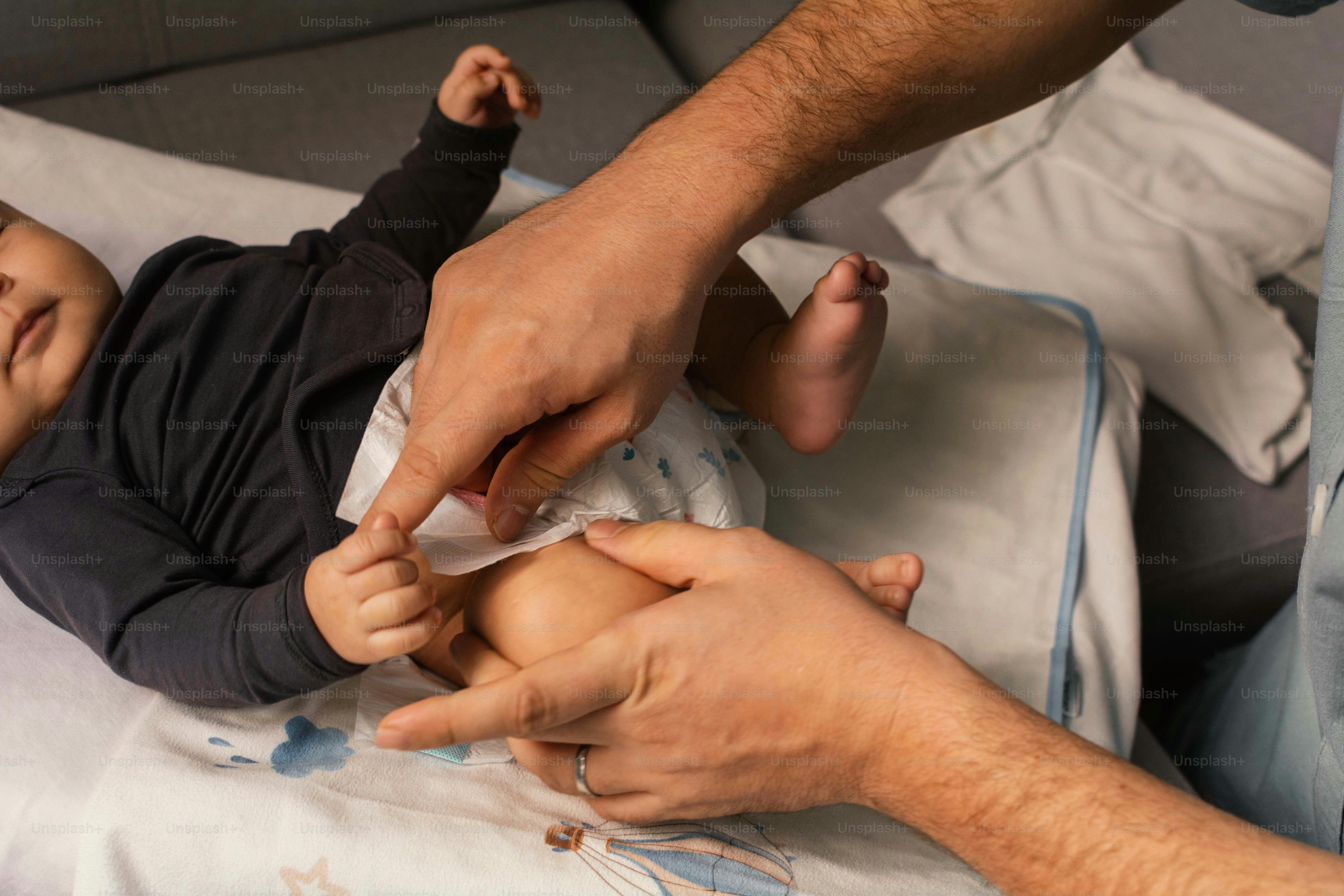 Parent qui change la couche d’un bébé sur une table à langer