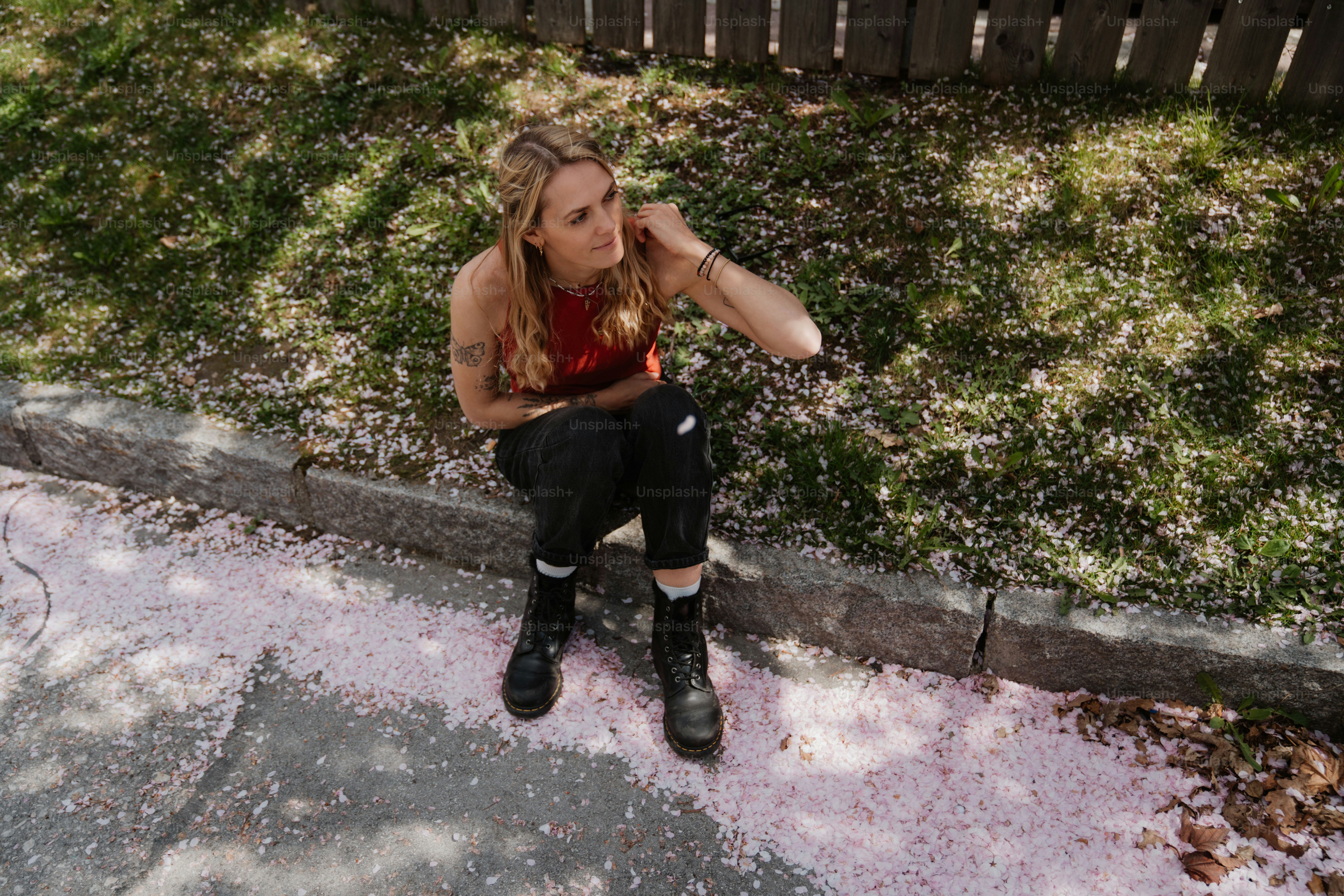 Woman sitting on the curb surrounded by pink petals