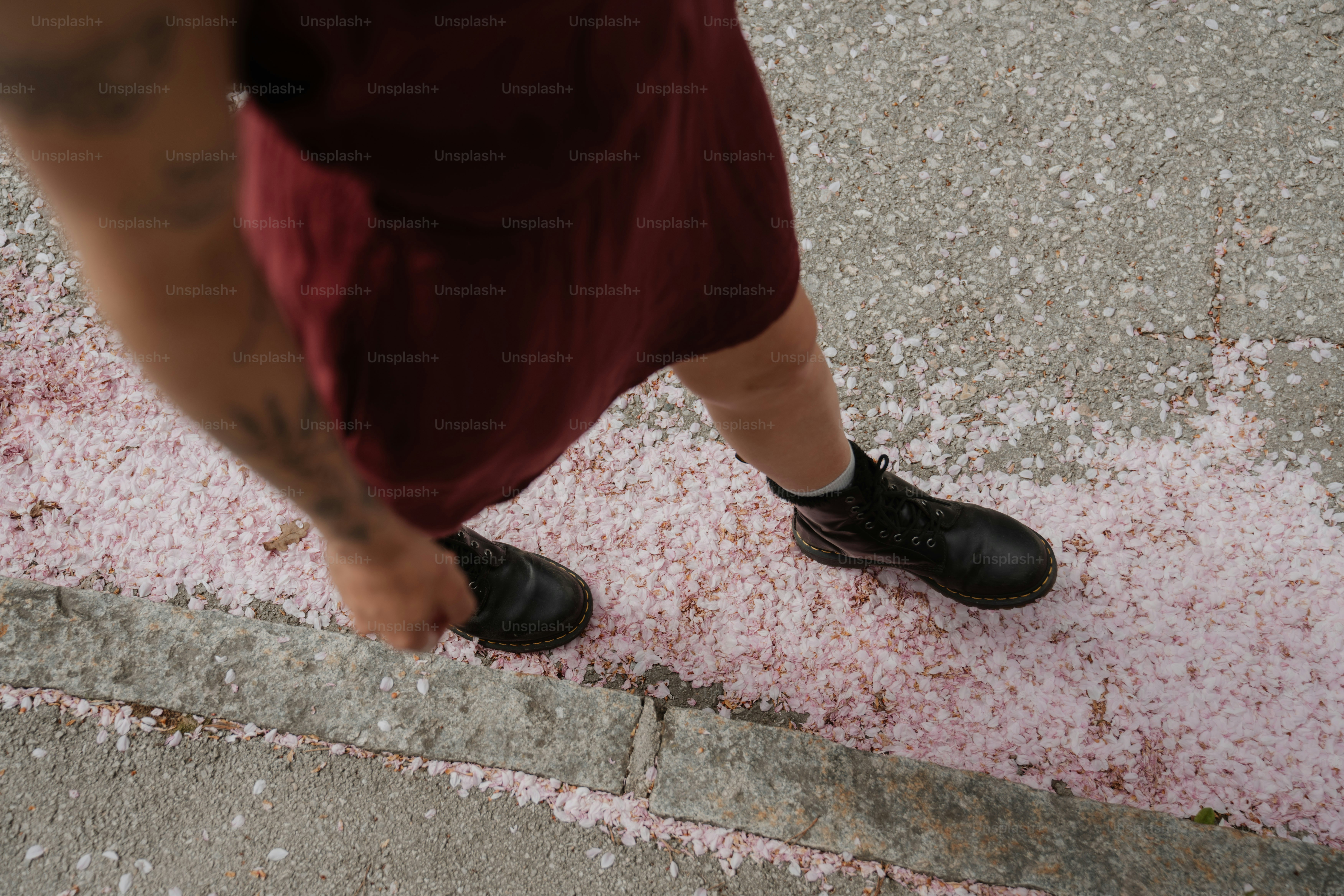 Person walking on a path covered in pink petals