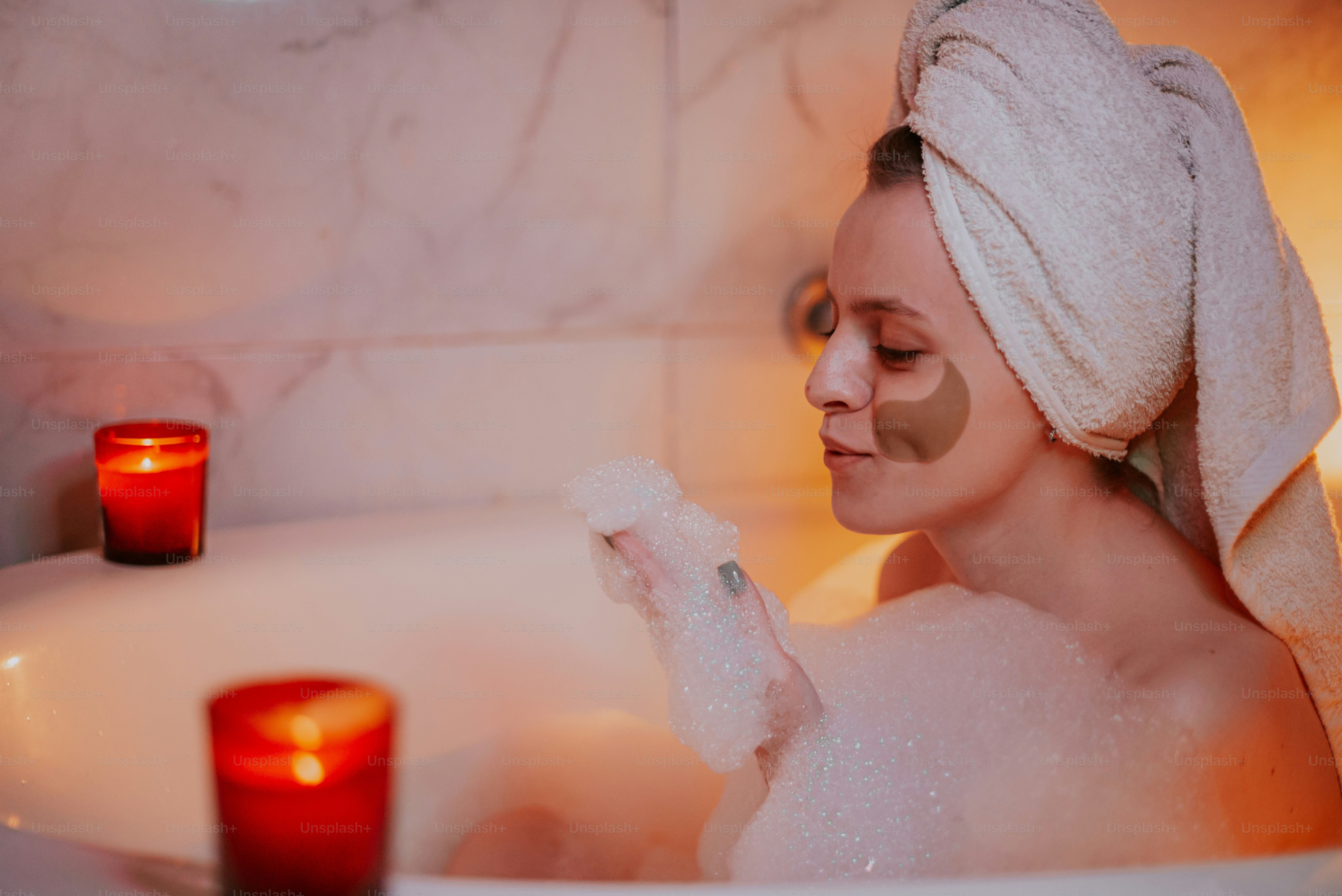 Woman with eye patches relaxes in a bubble bath.