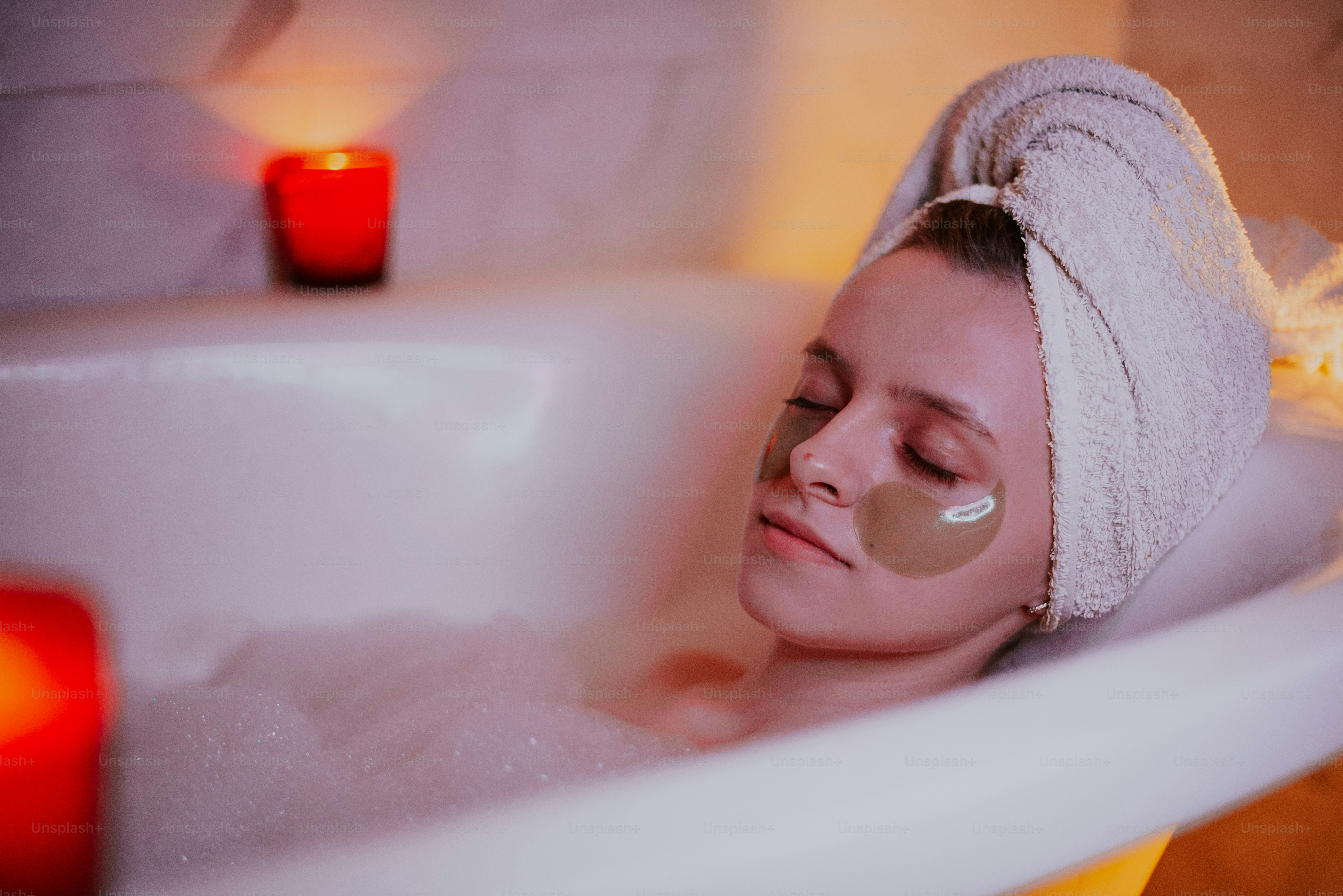 Woman relaxing in a bubble bath with eye patches.
