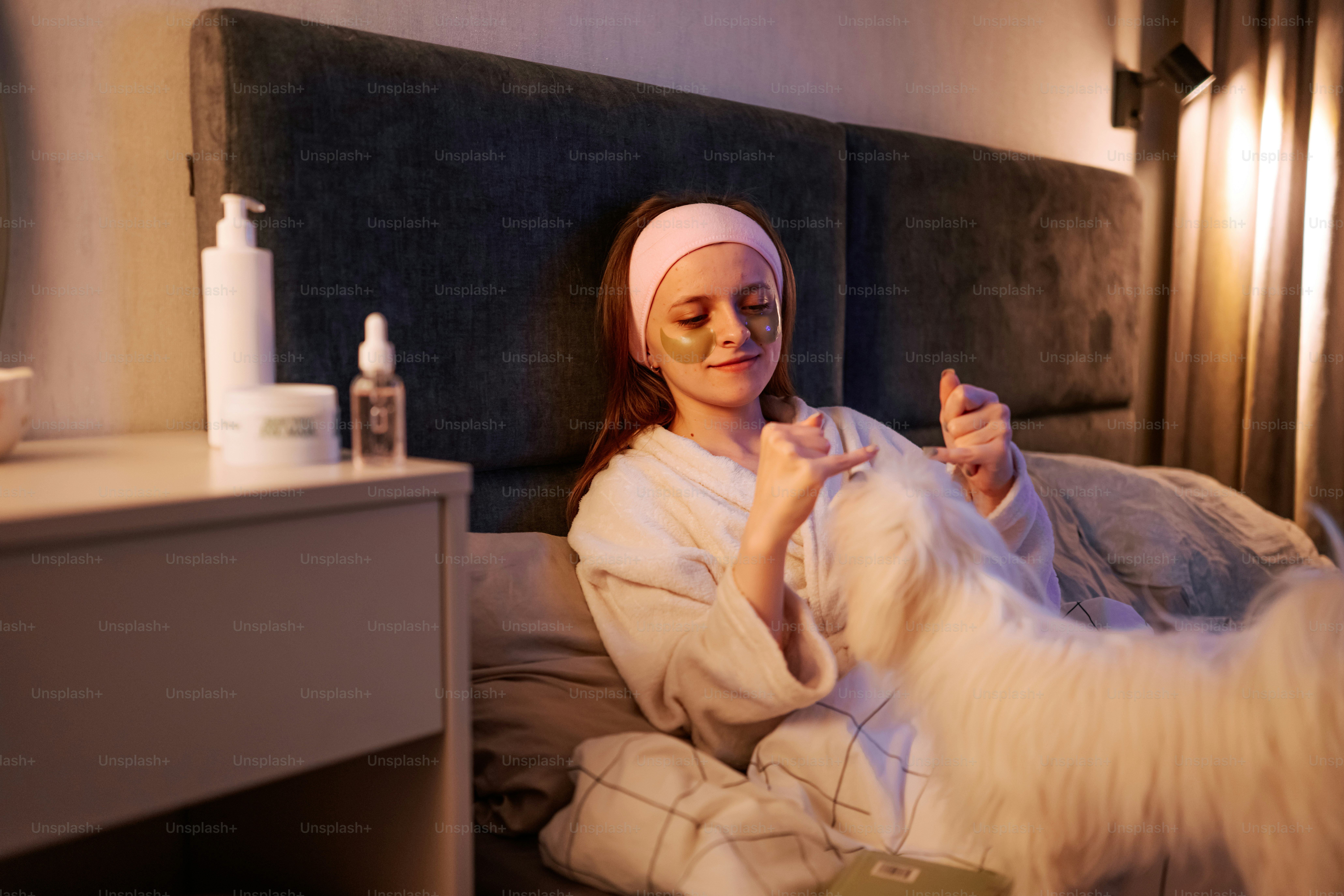 Woman in bed with skincare and a fluffy dog