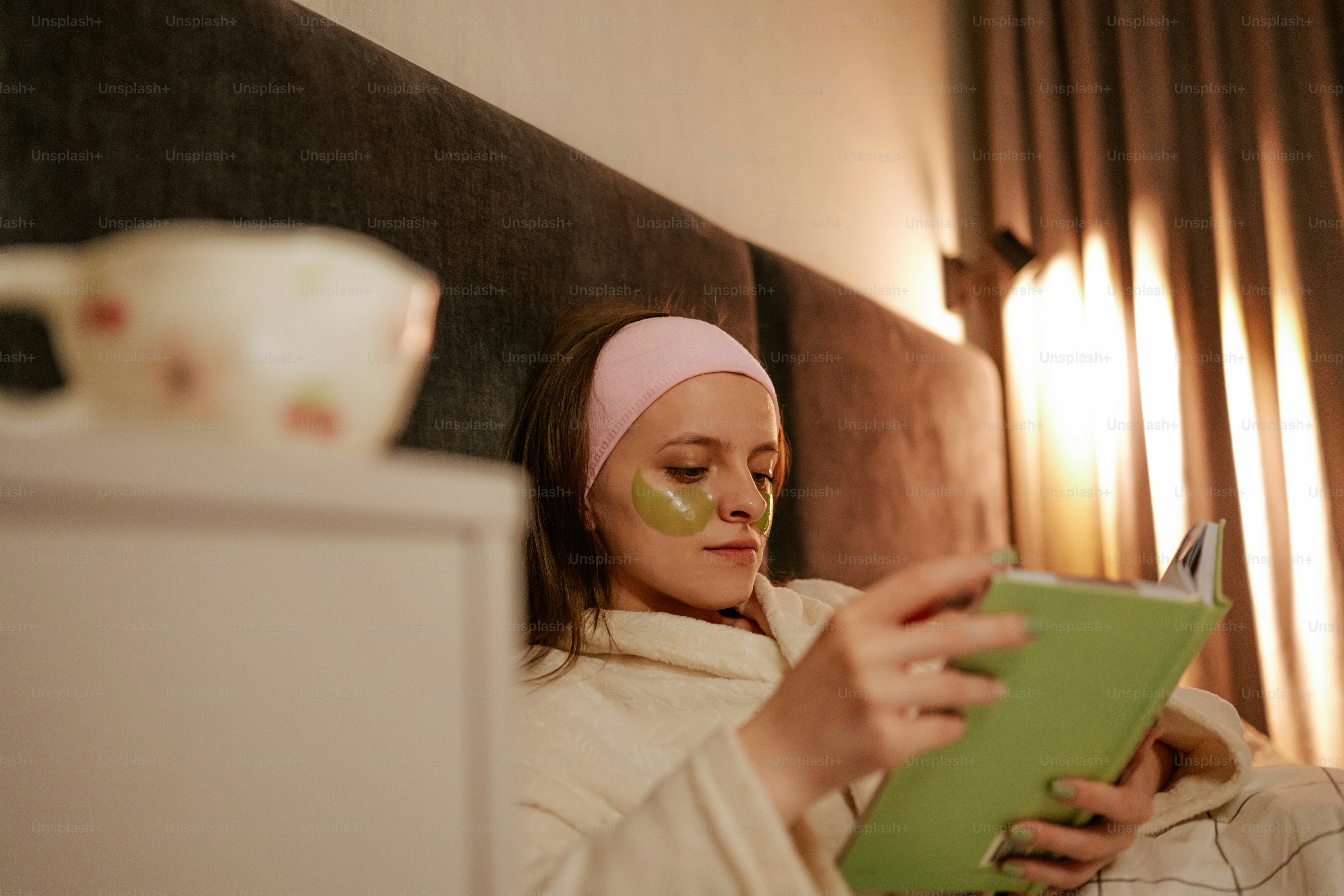 Woman reading a book with eye patches on.