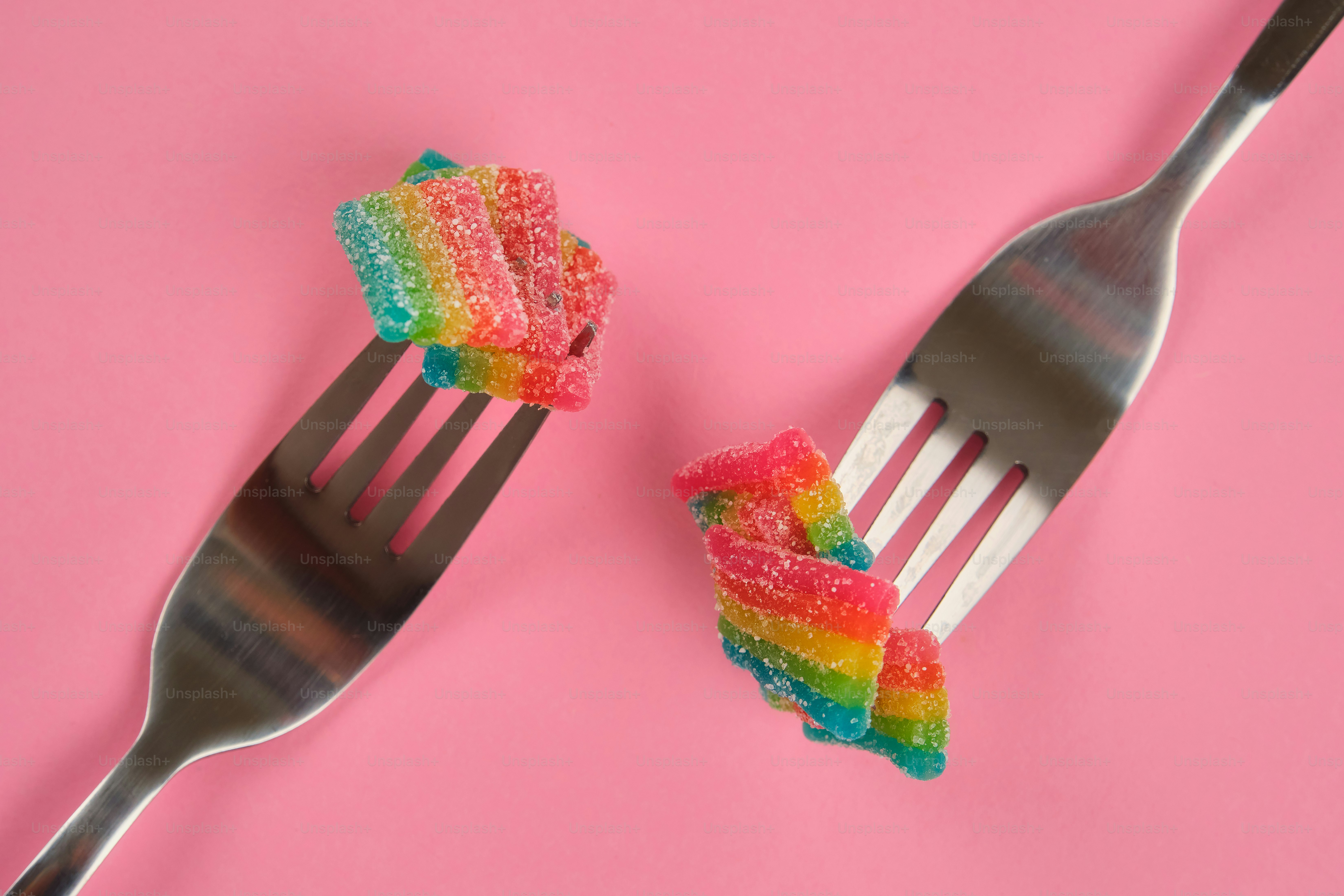 Two forks holding rainbow sour candy strips
