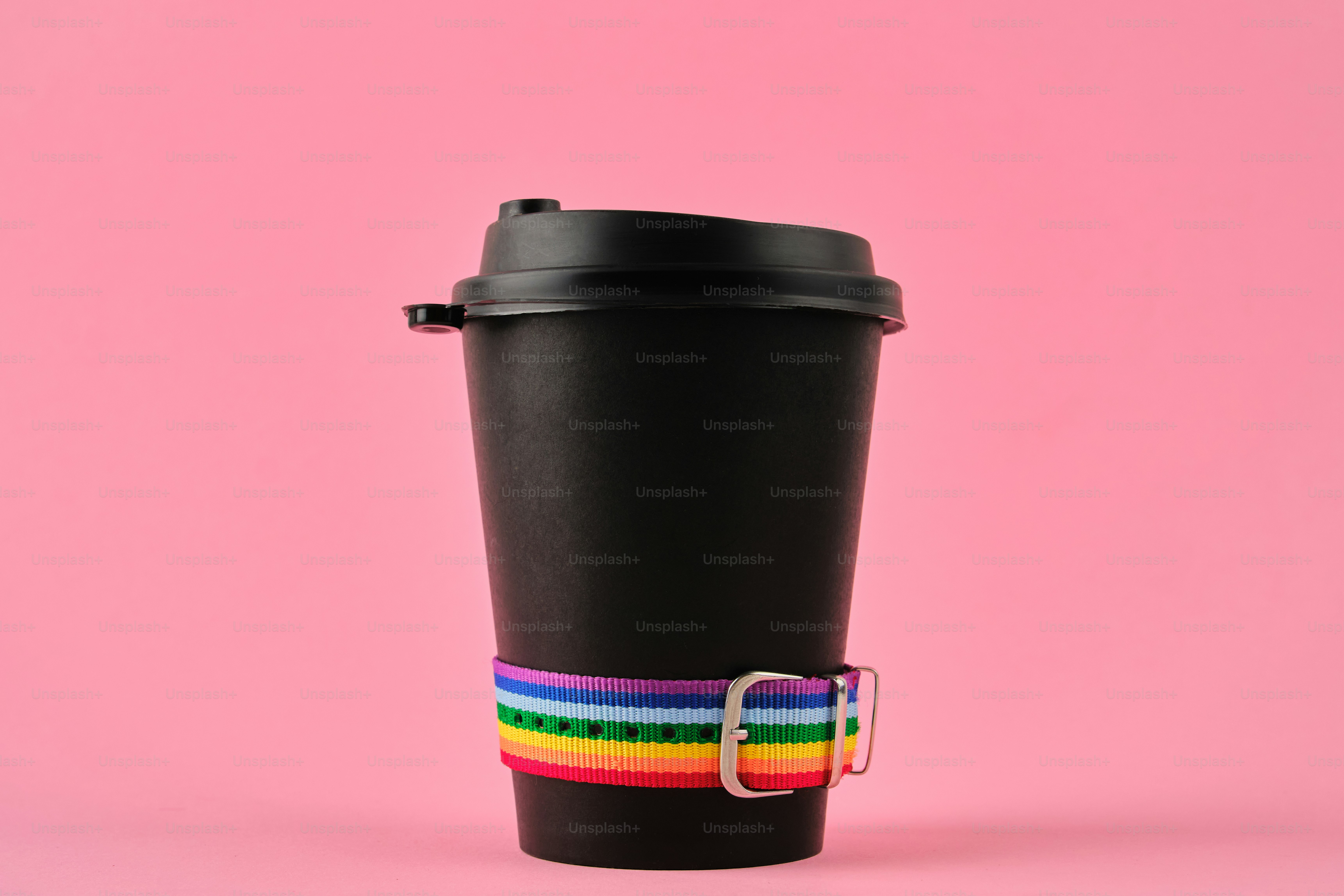 Black coffee cup with rainbow band on pink background