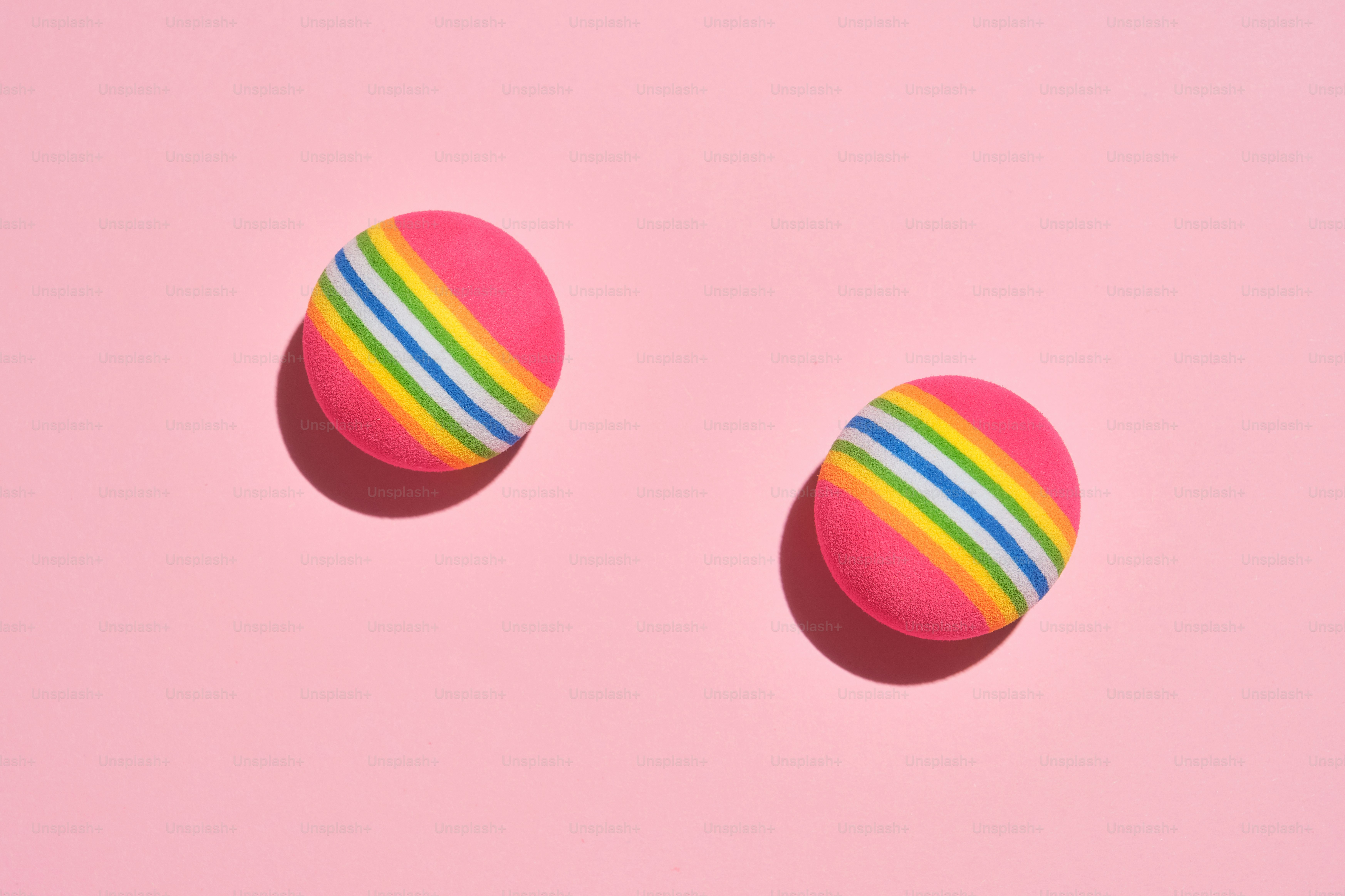 Two pink balls with rainbow stripes on pink