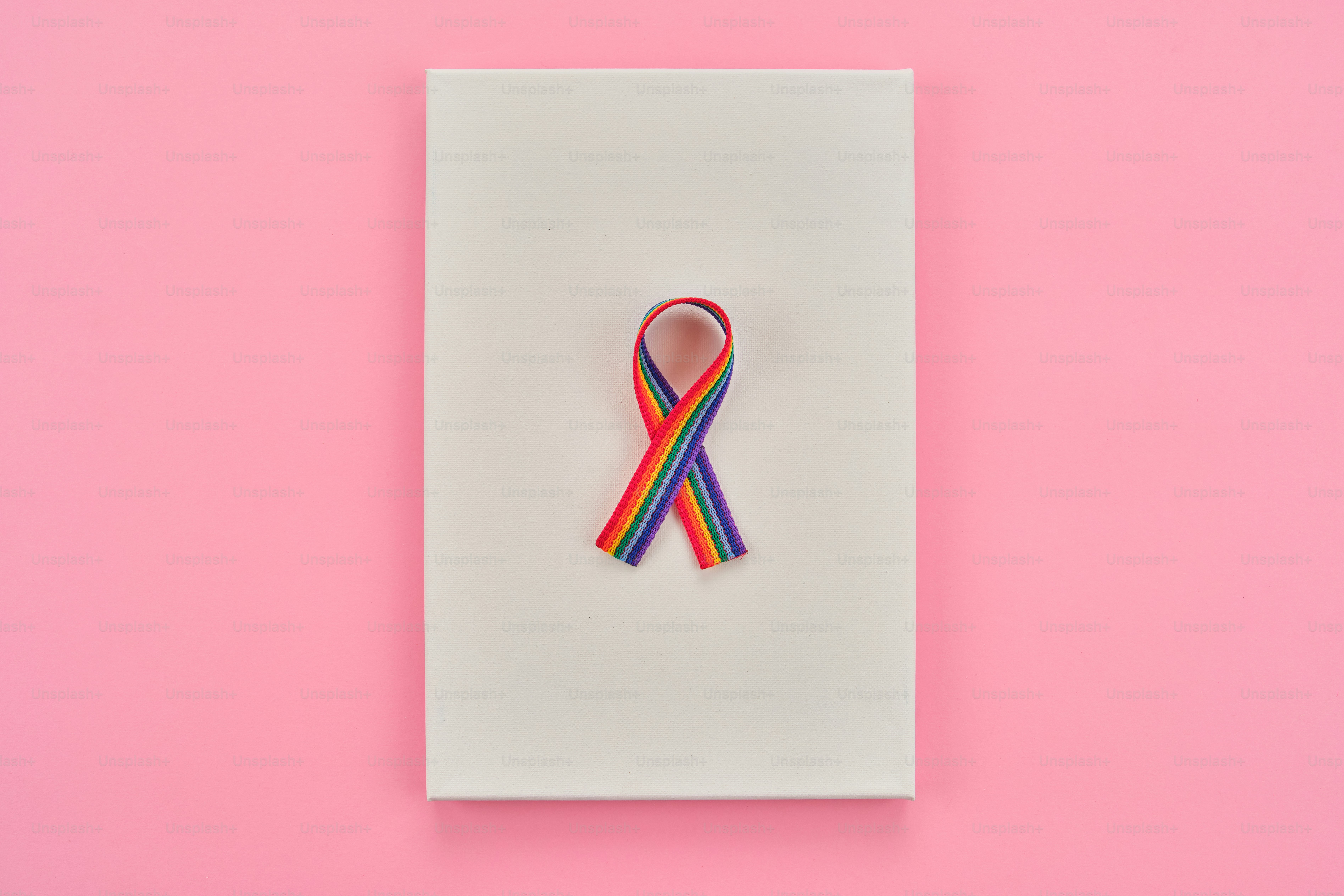 Rainbow ribbon on a white surface against pink background