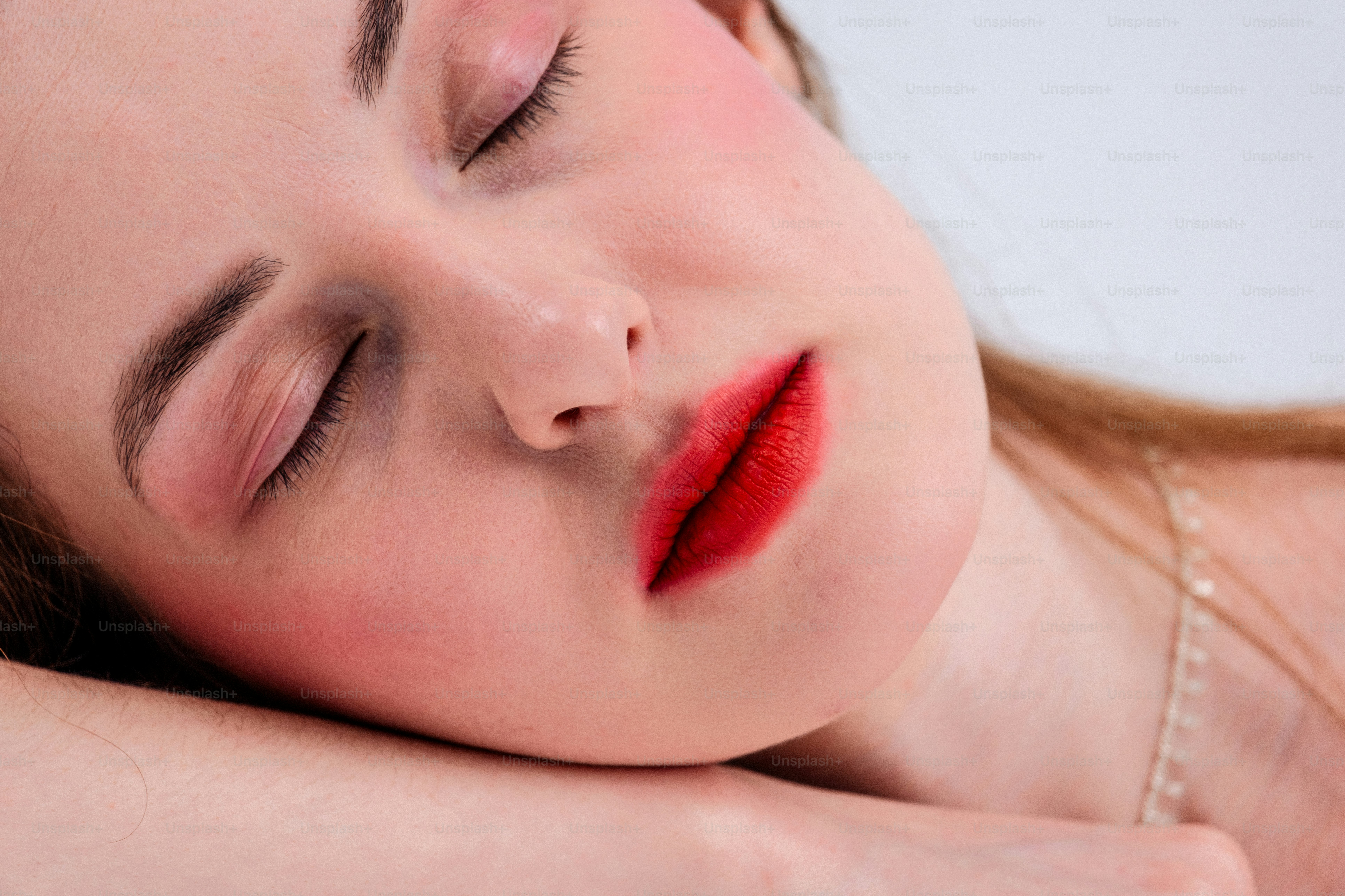 Una mujer con pintalabios rojo y rubor durmiendo