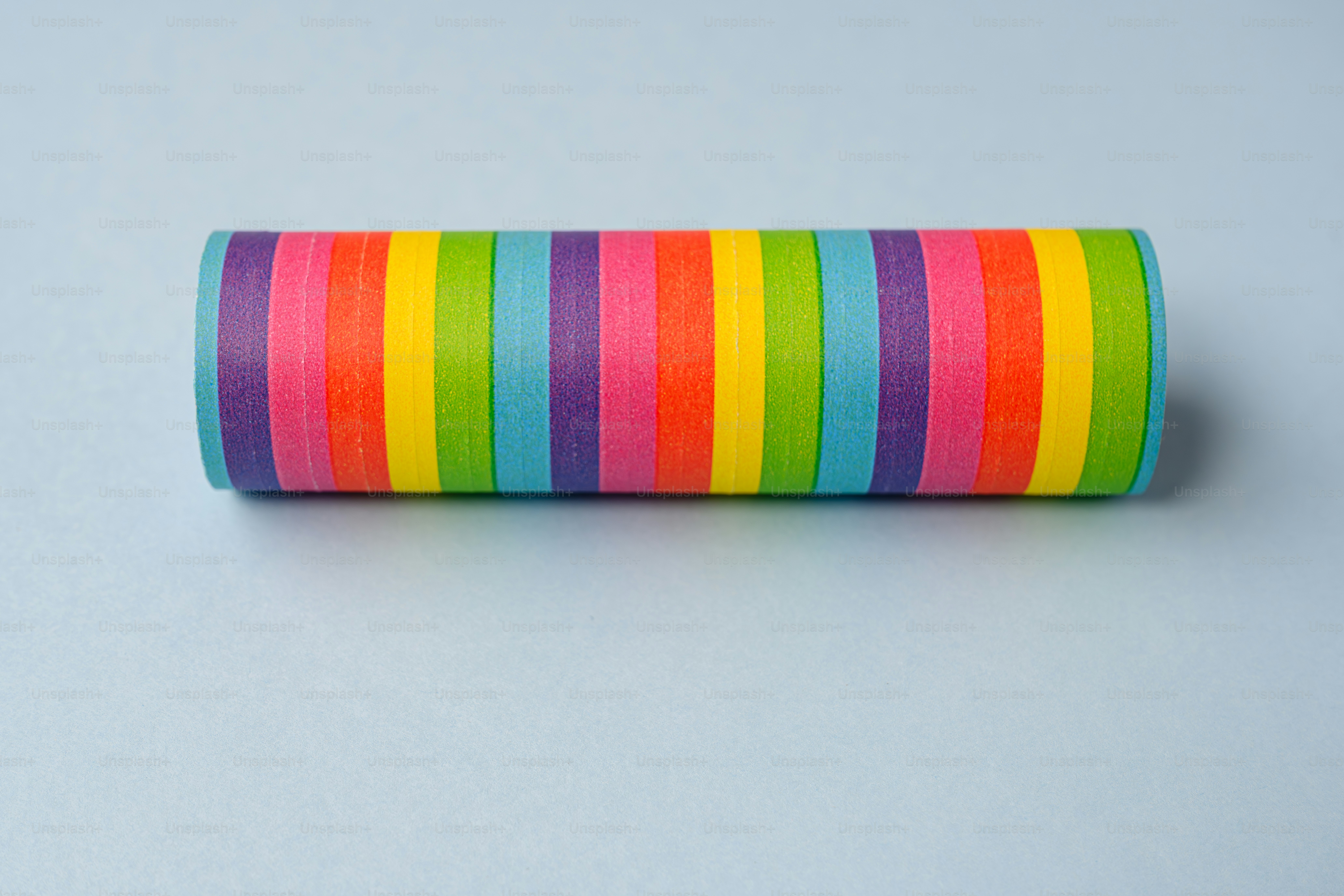 Objek silinder dengan garis-garis pelangi dengan latar belakang biru