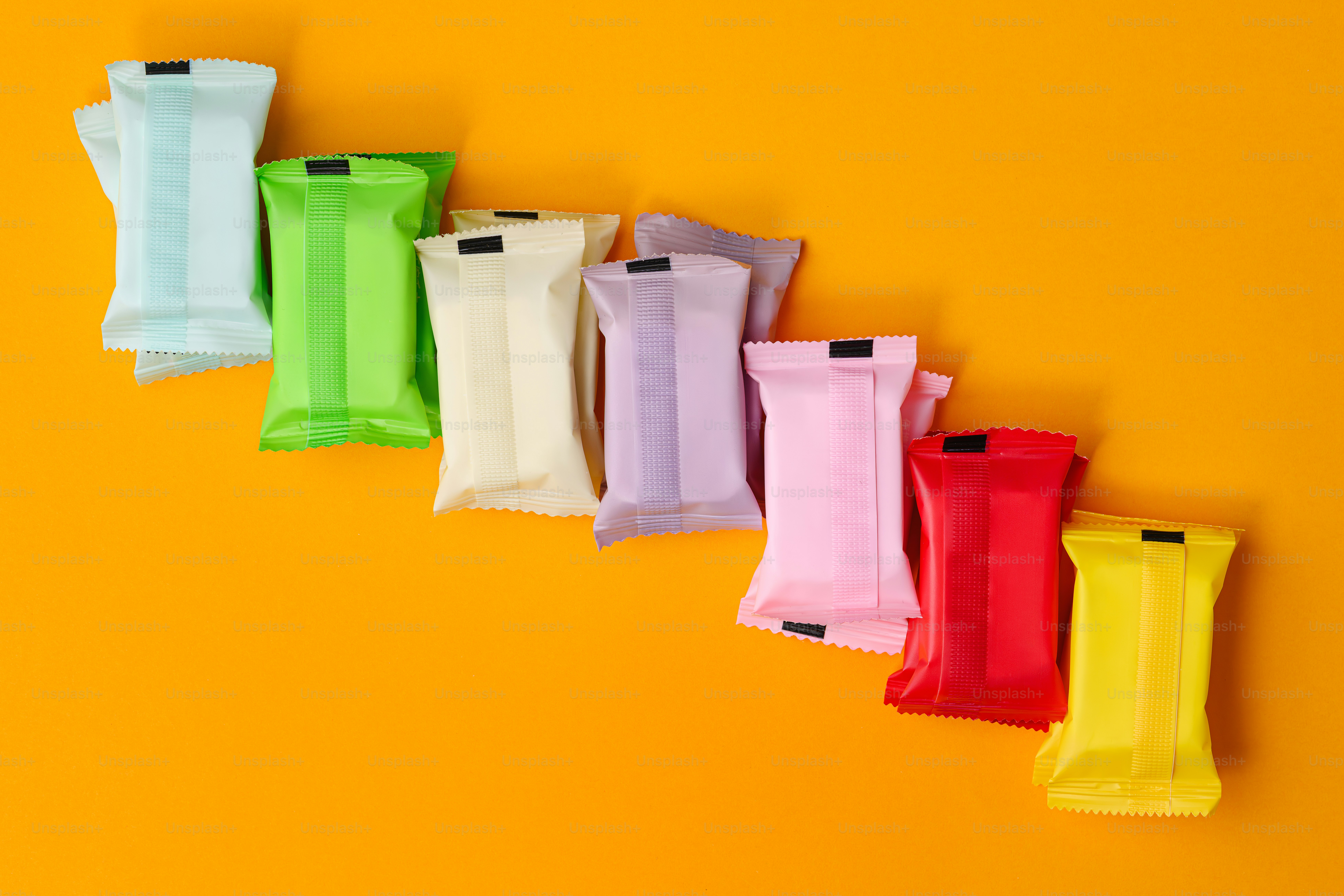 Row of colorful wrapped candies on orange background