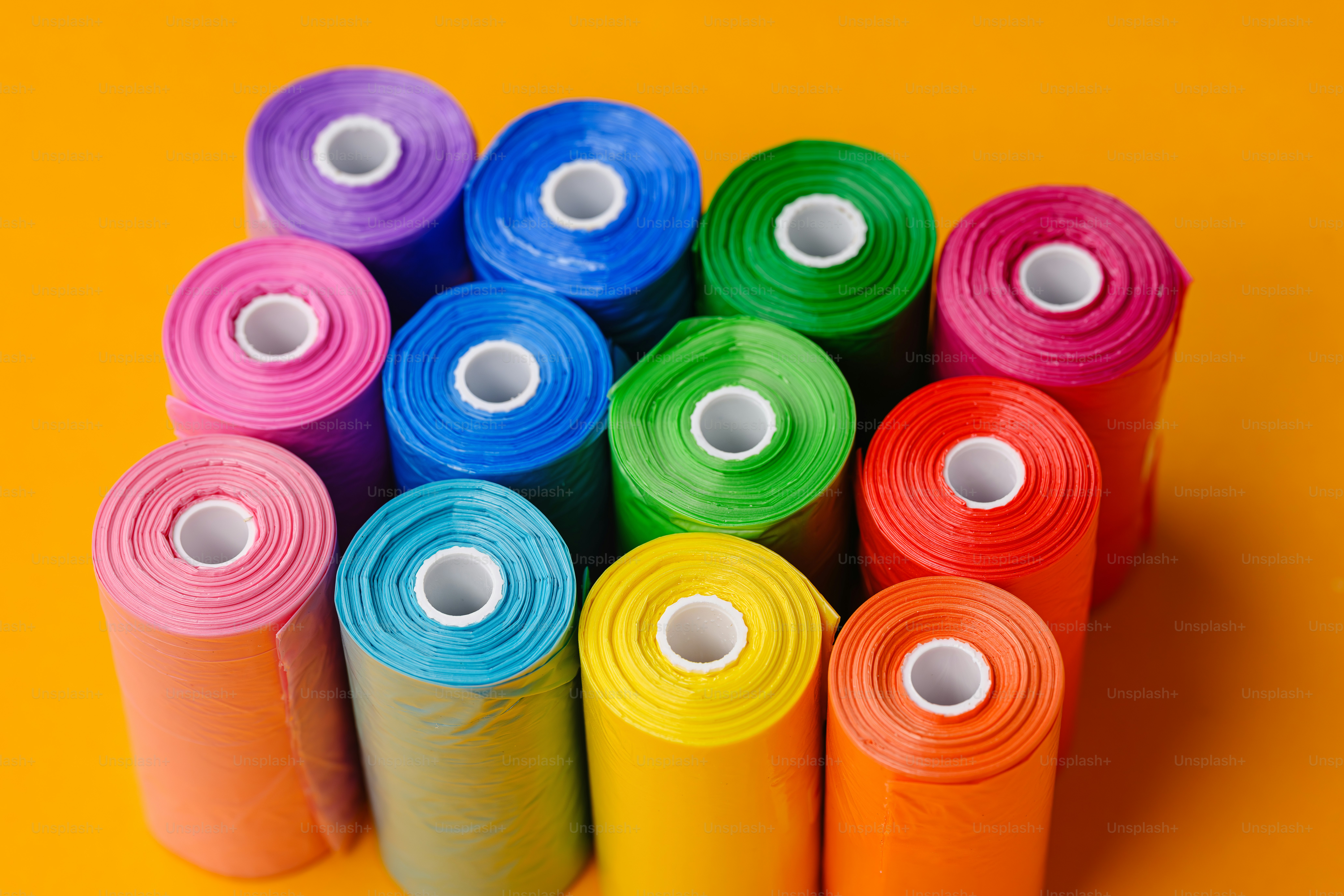 Rollen aus bunten Plastiktüten auf orangem Hintergrund
