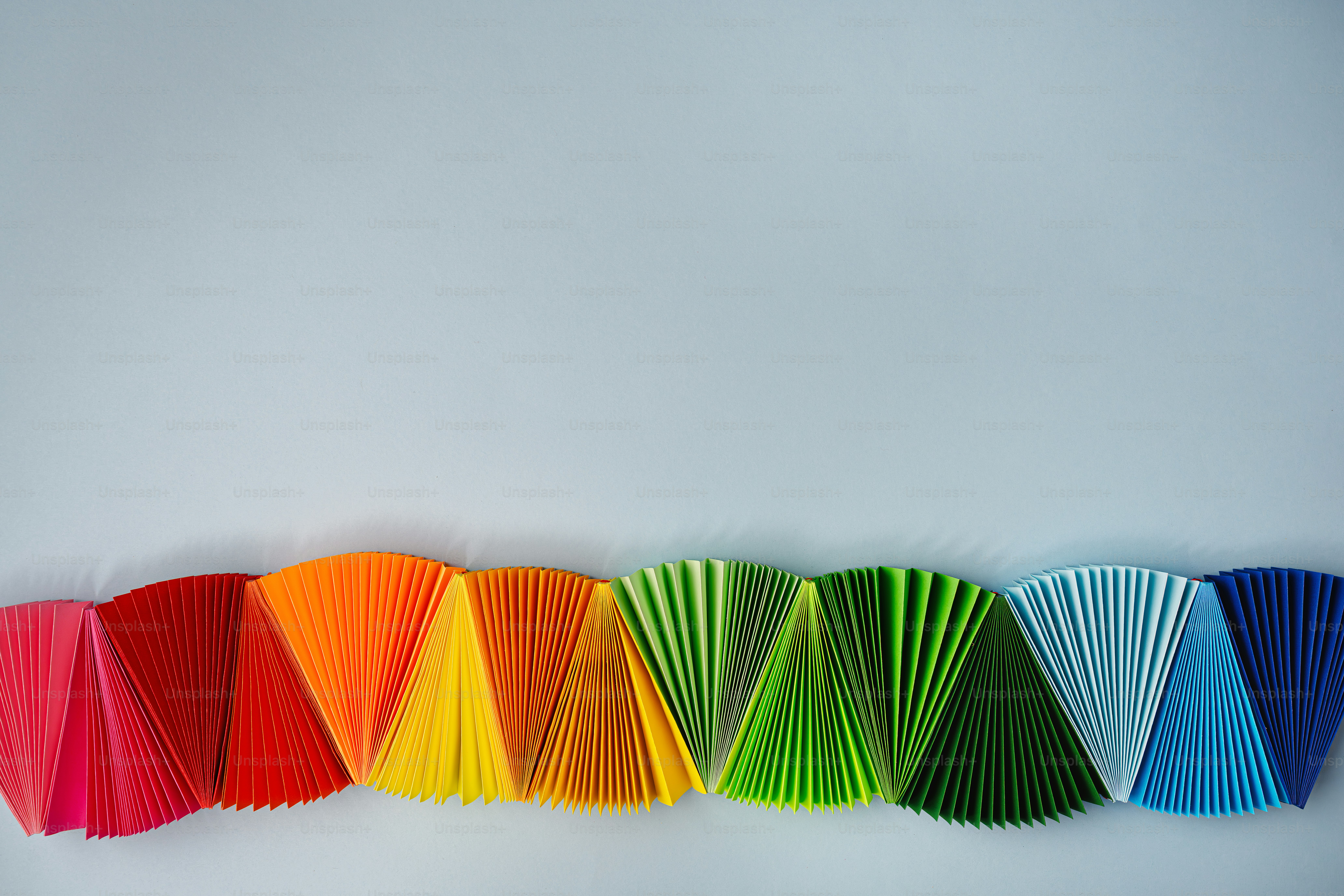 Colorful paper fans arranged in a rainbow spectrum.