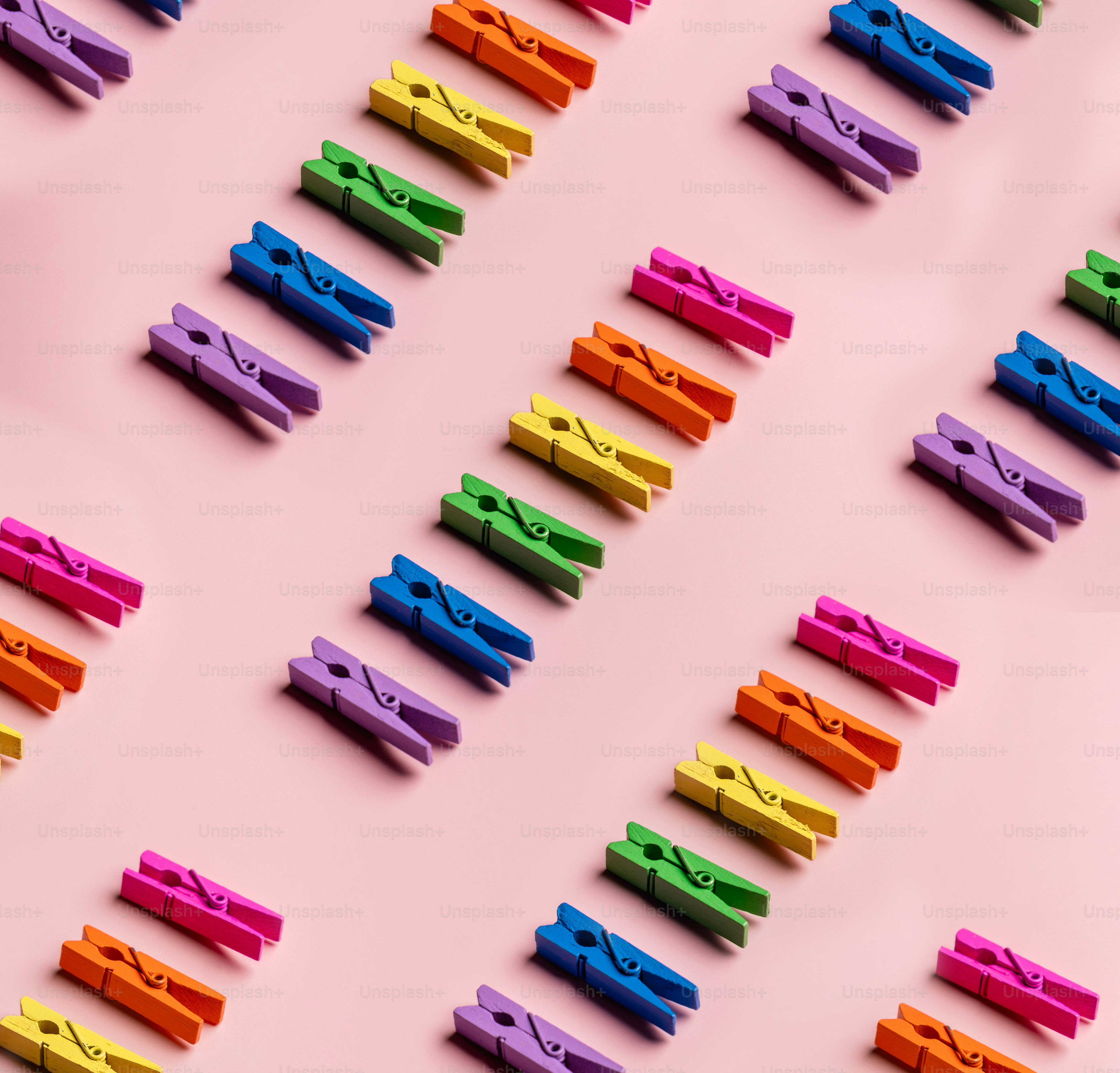 Colorful clothespins arranged in diagonal rows on pink background ...