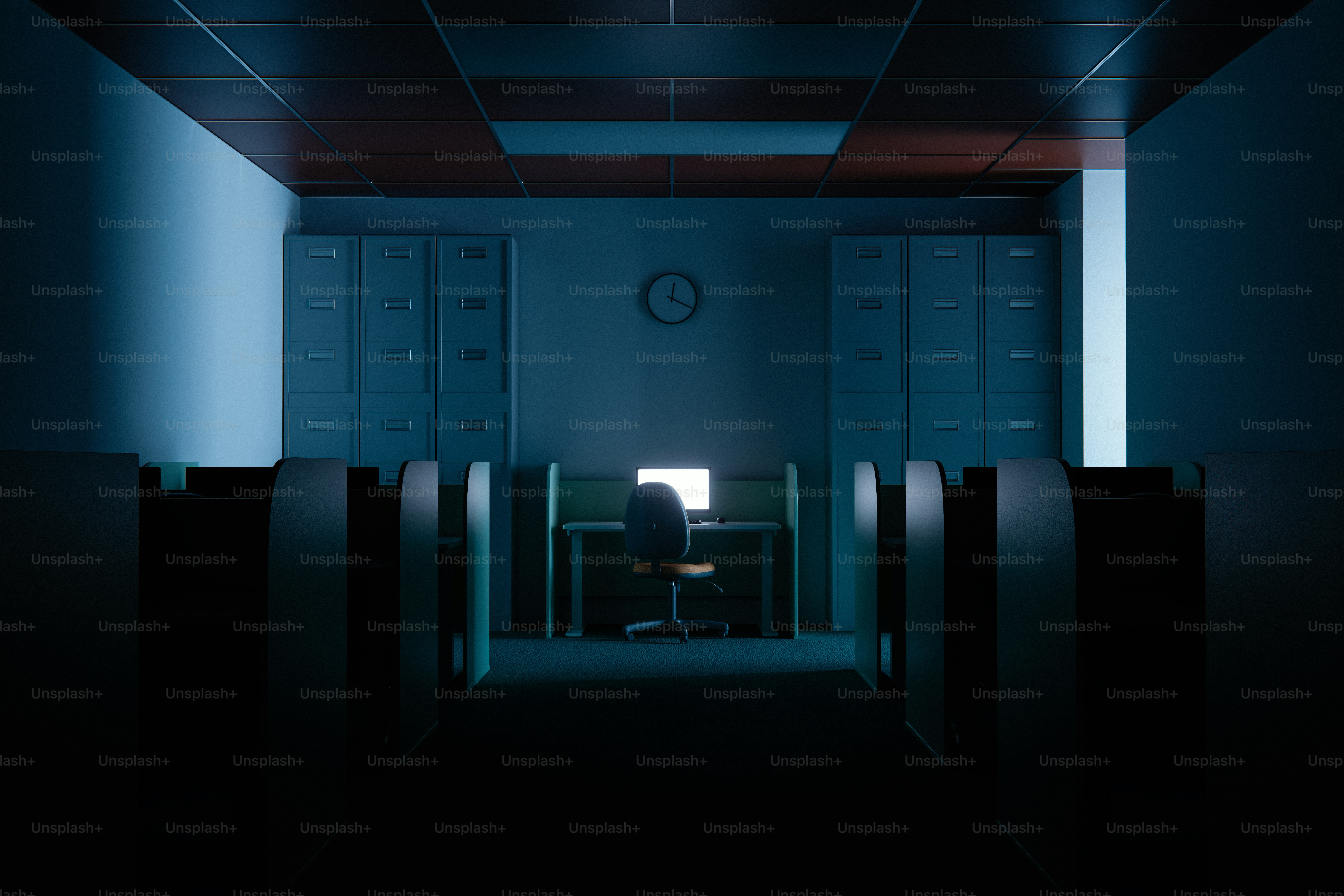 Empty office with a single illuminated computer workstation at desk