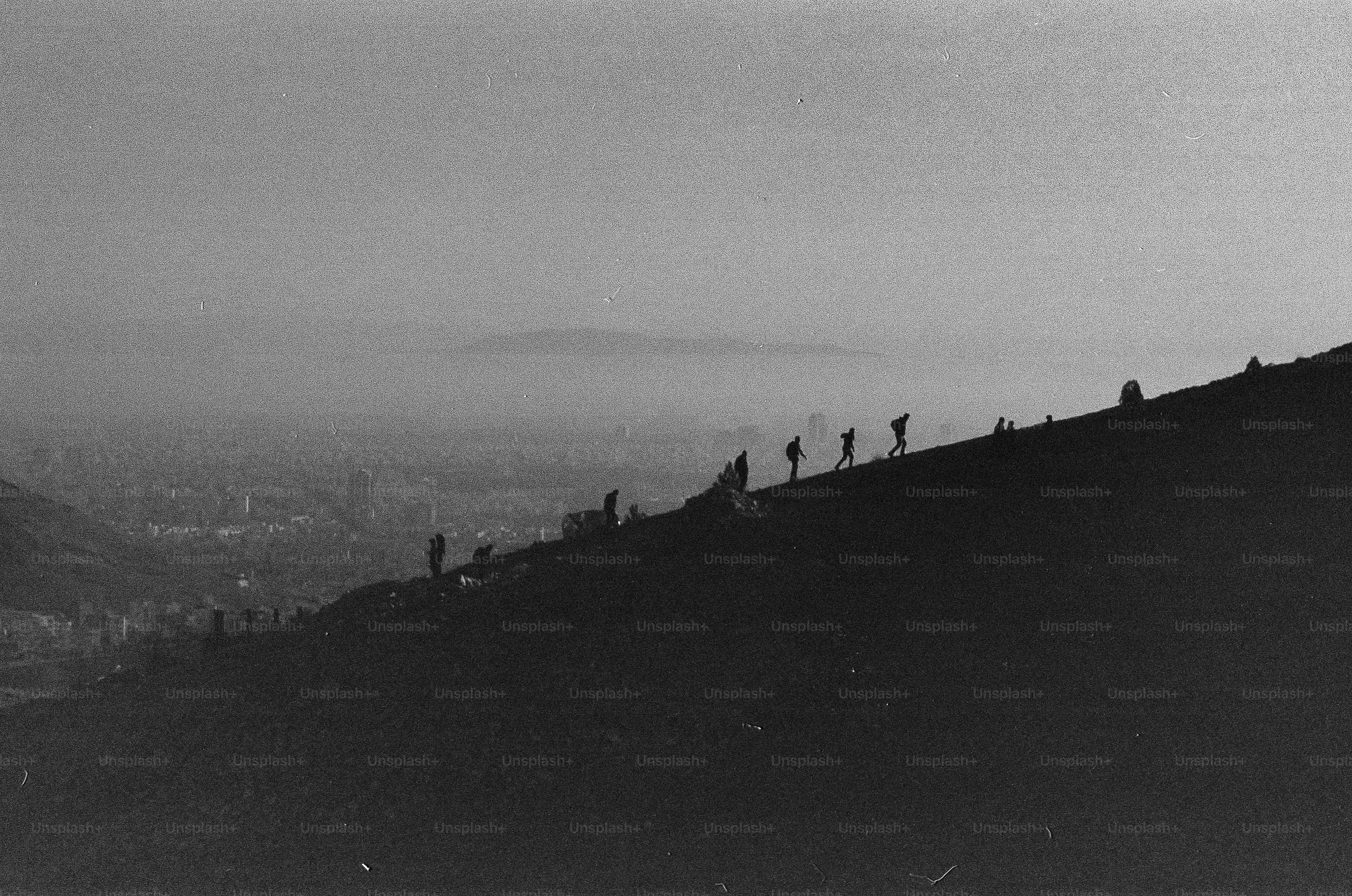 People walking along a mountain ridge overlooking a hazy city