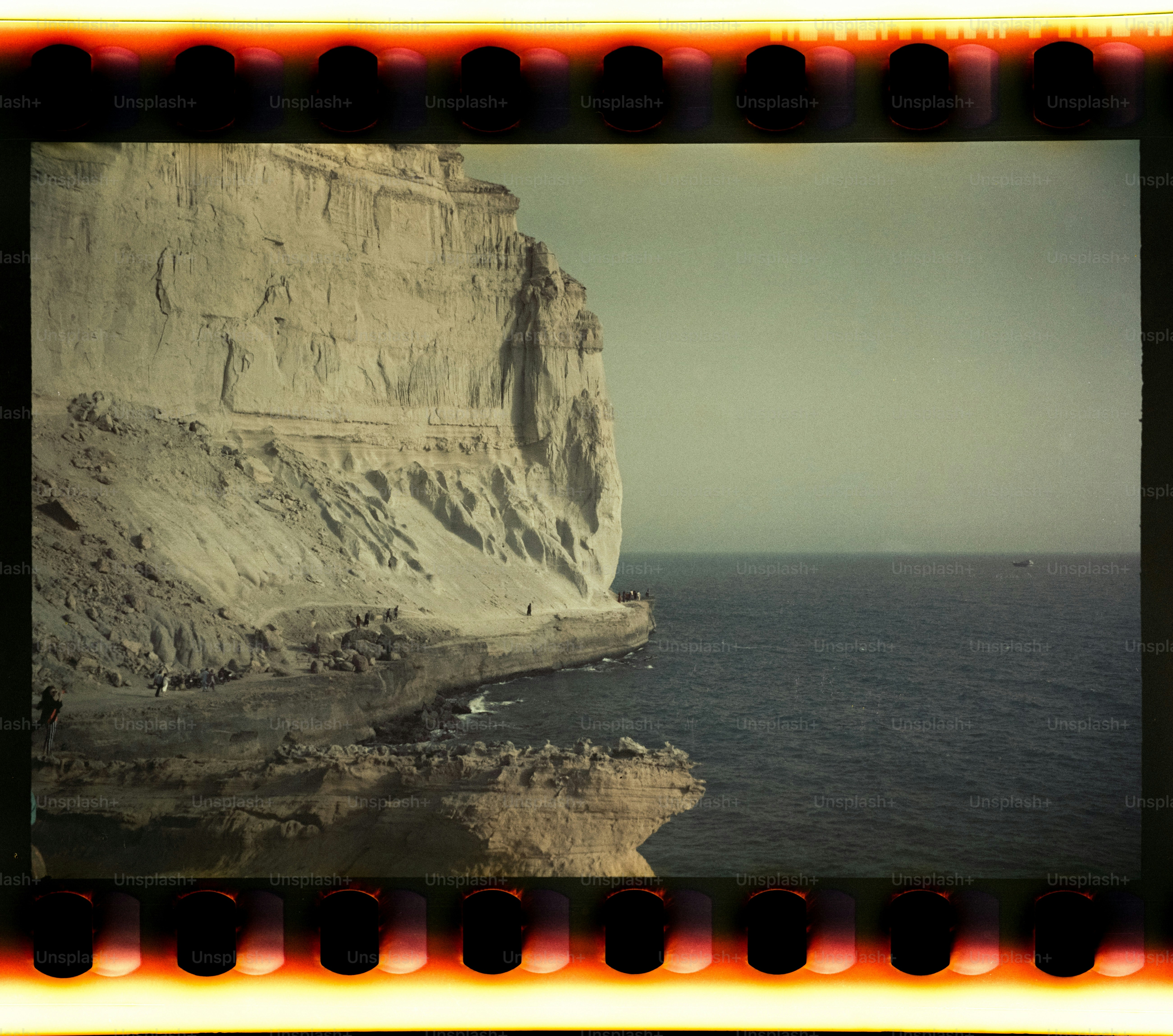 Rugged cliffs meet the calm sea under a hazy sky