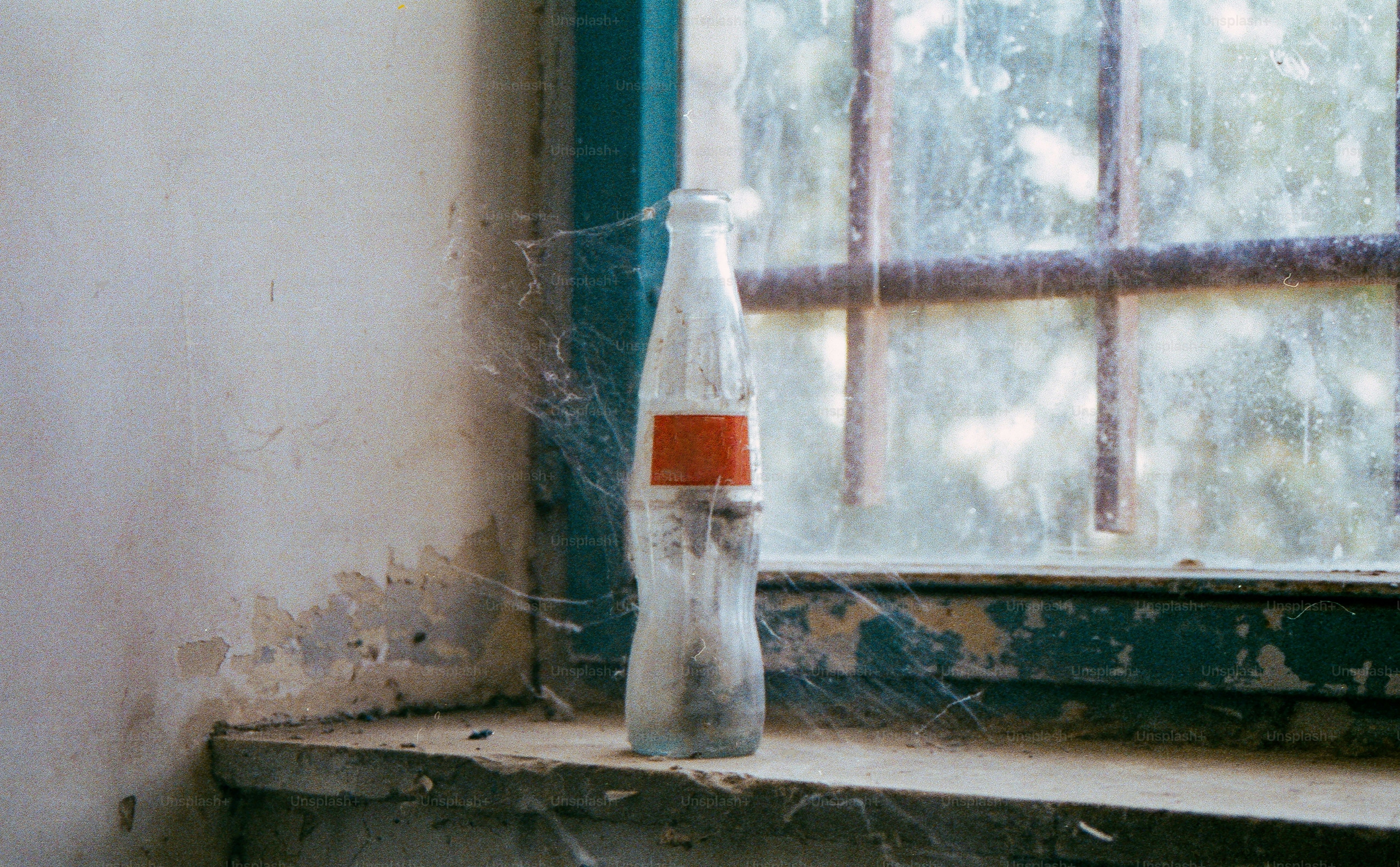 Glass bottle with orange label on dusty windowsill