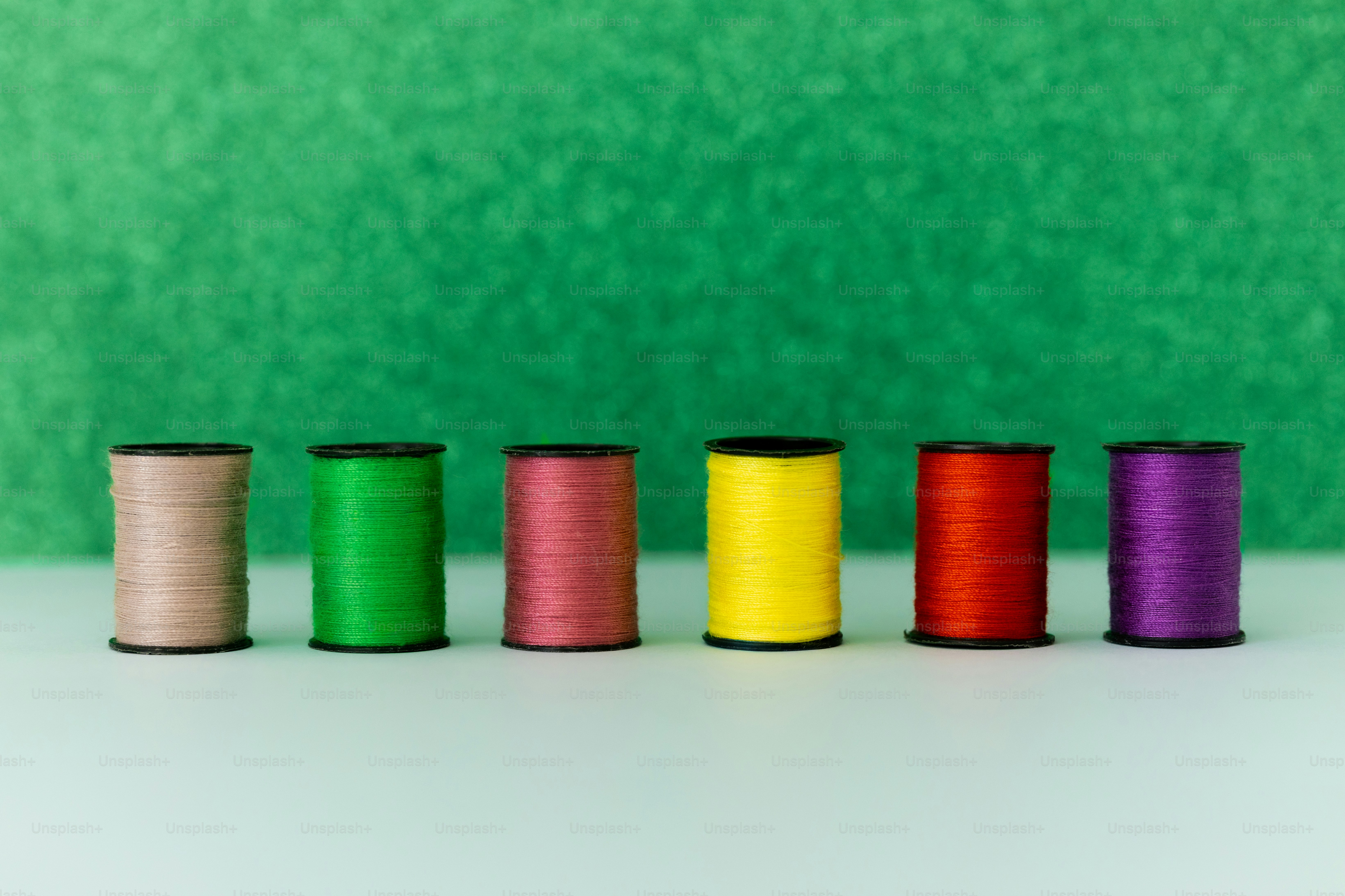 Six spools of colorful thread on a green background photo – Fabric ...