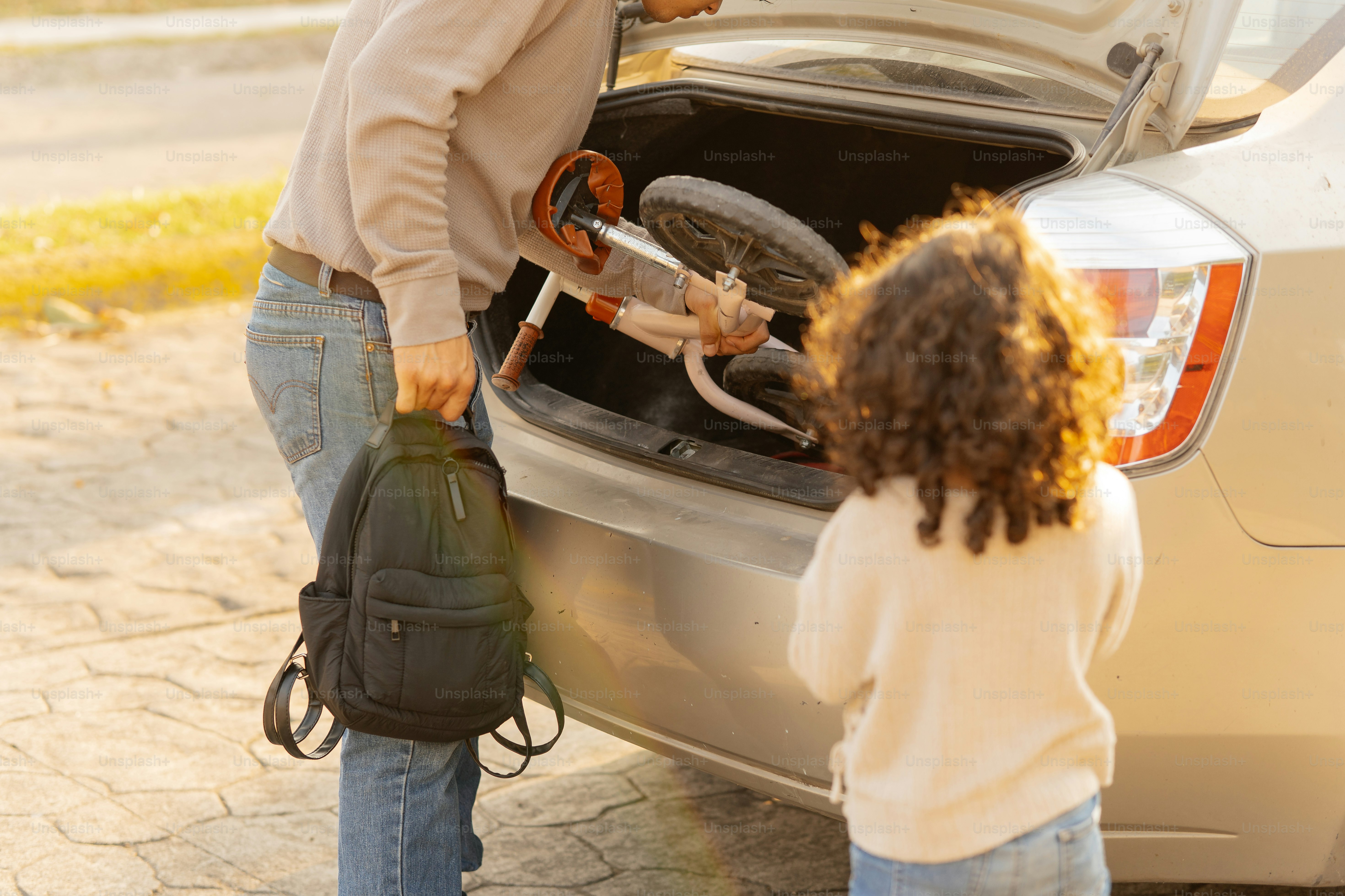 Homme chargeant le vélo d’un enfant dans le coffre de la voiture