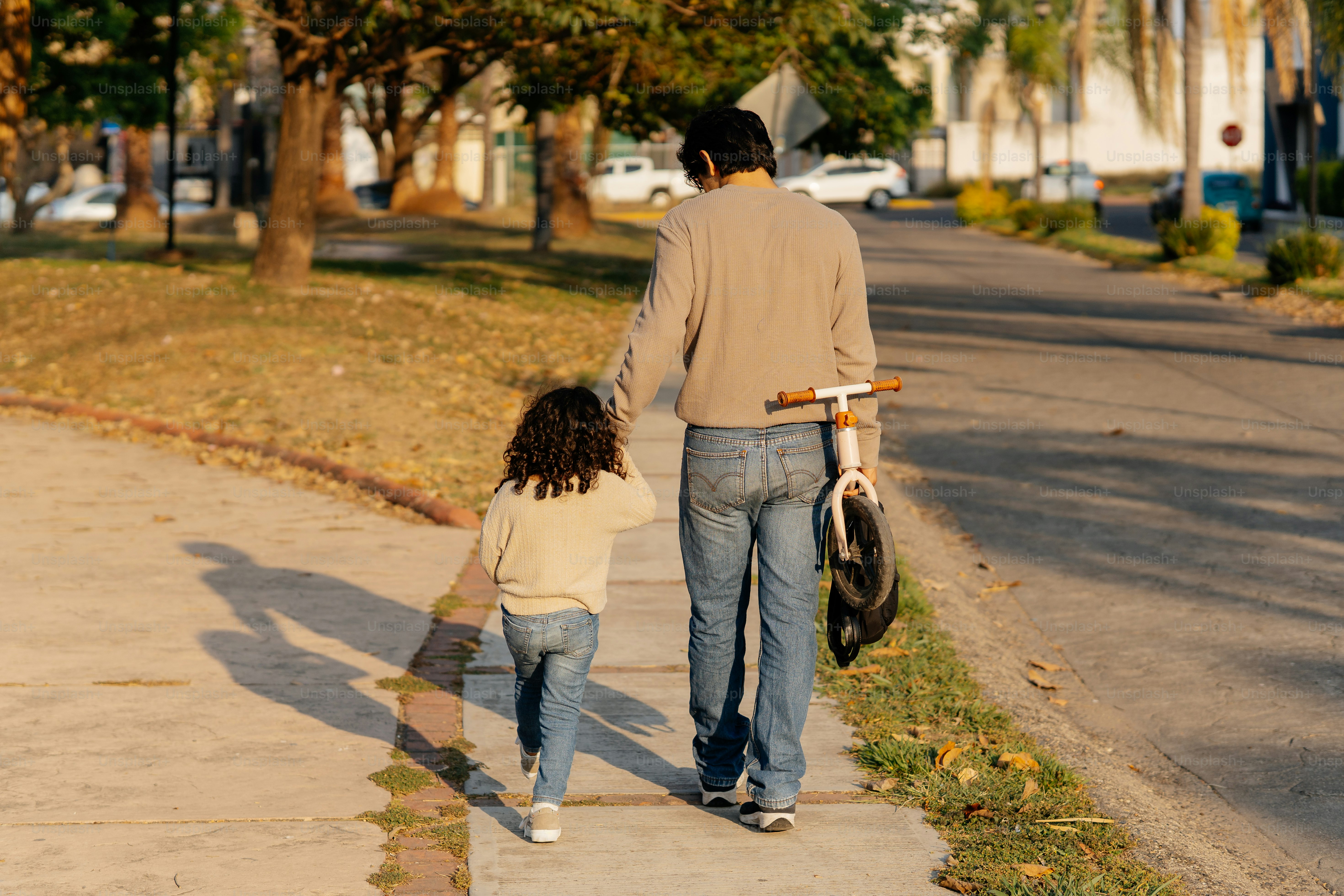 Père et enfant marchent sur le trottoir en se tenant la main