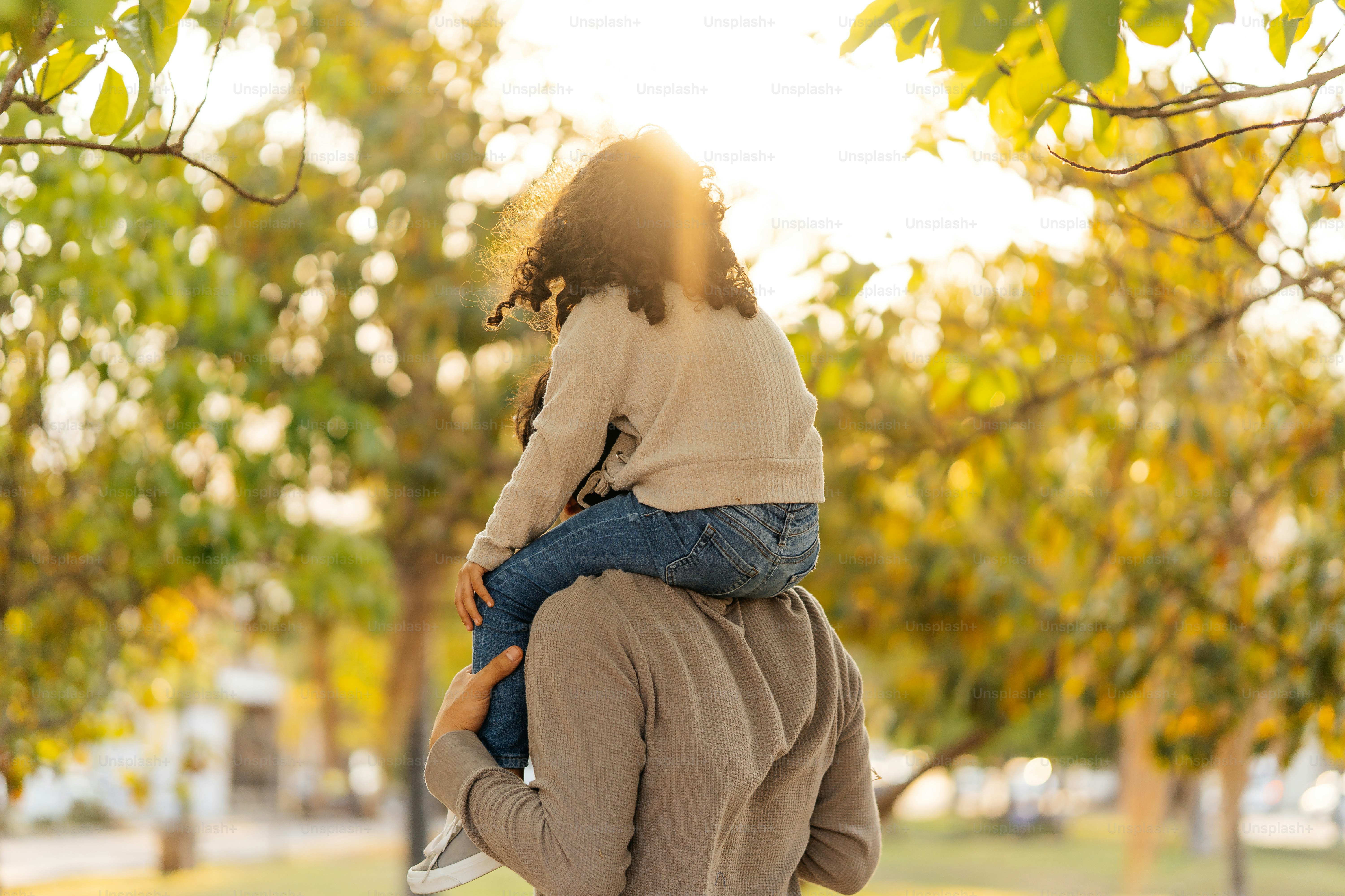 Père portant sa fille sur les épaules dans le parc