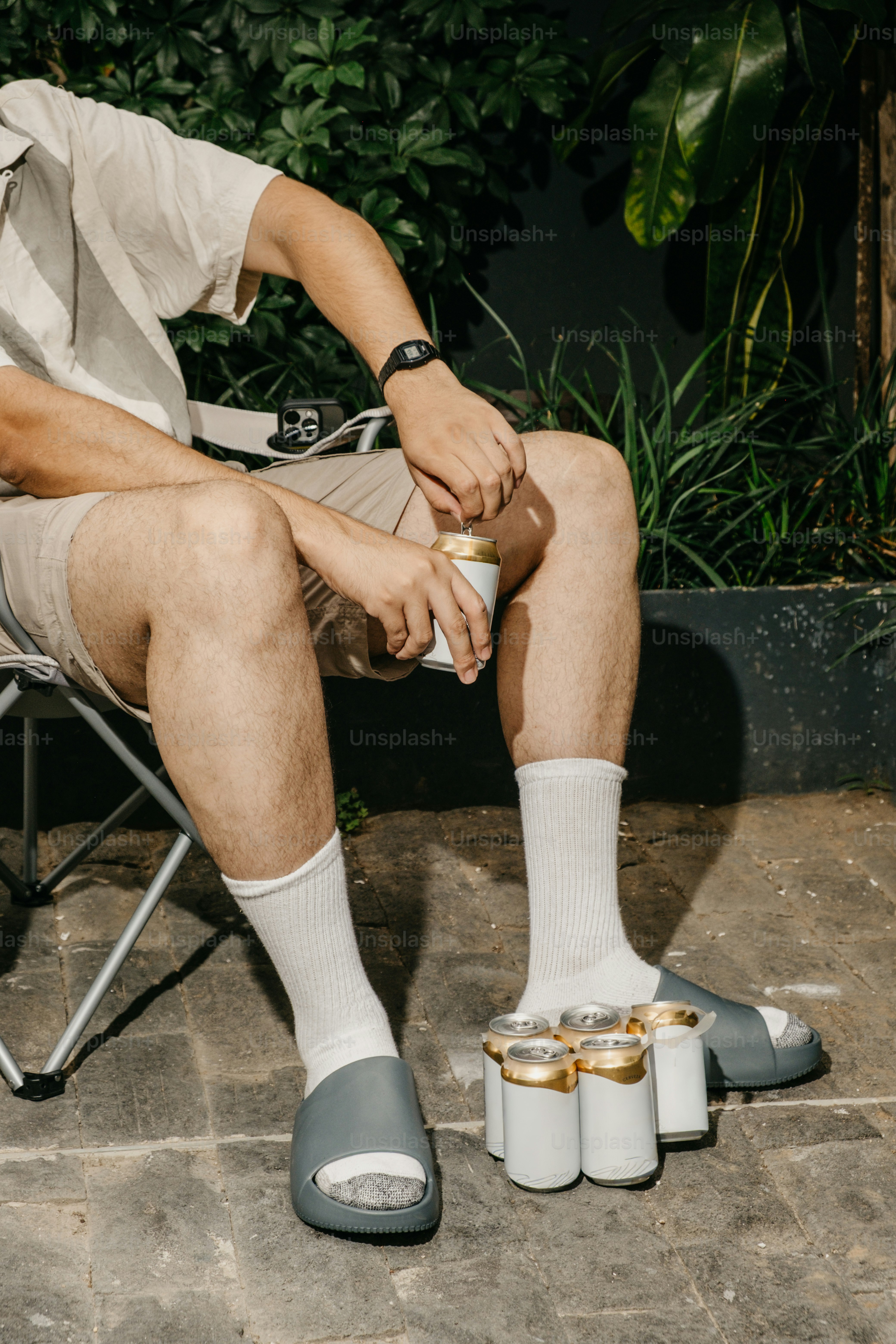 Hombre sentado con latas de cerveza entre los pies