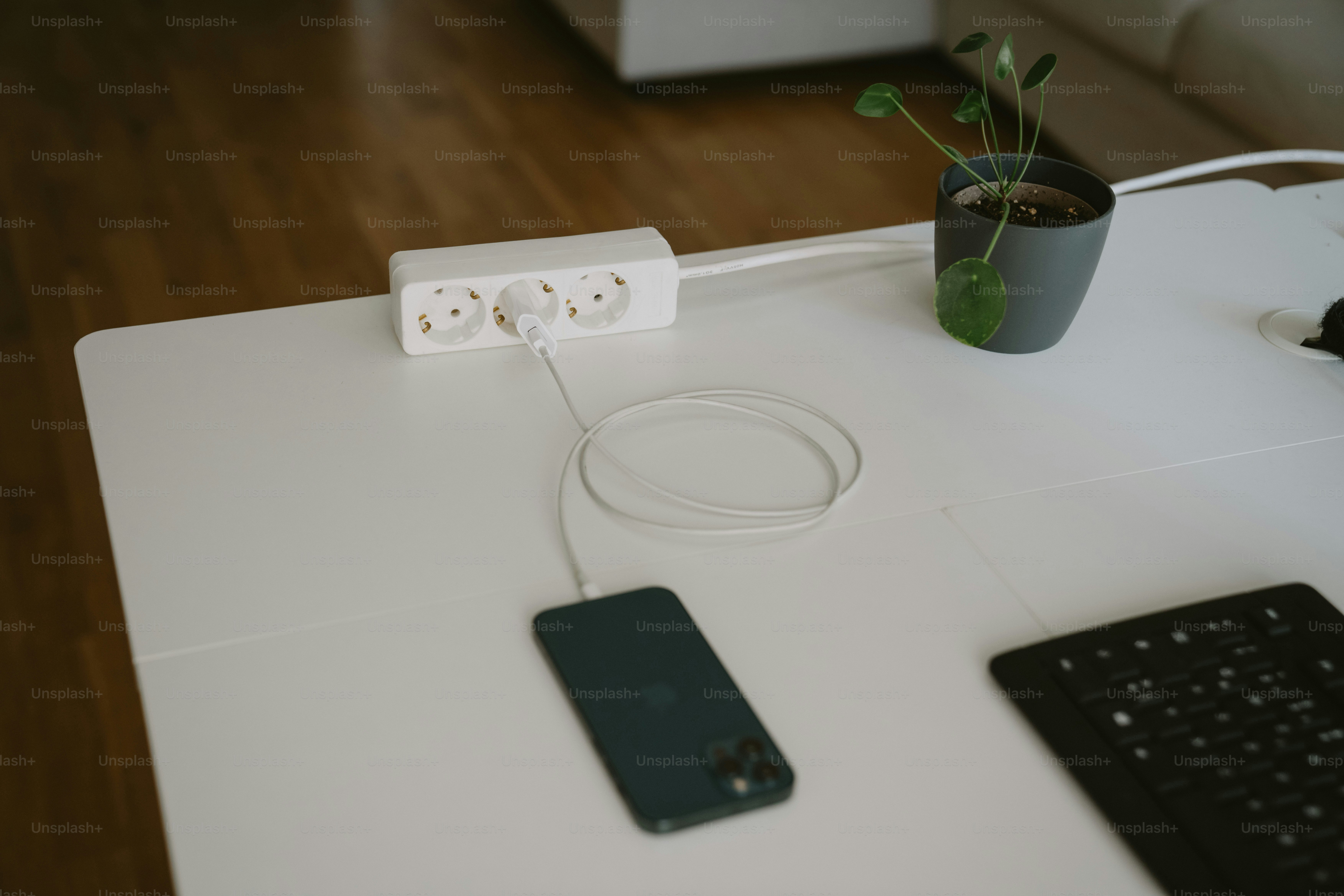 Ricarica dello smartphone su una scrivania bianca con una ciabatta elettrica.