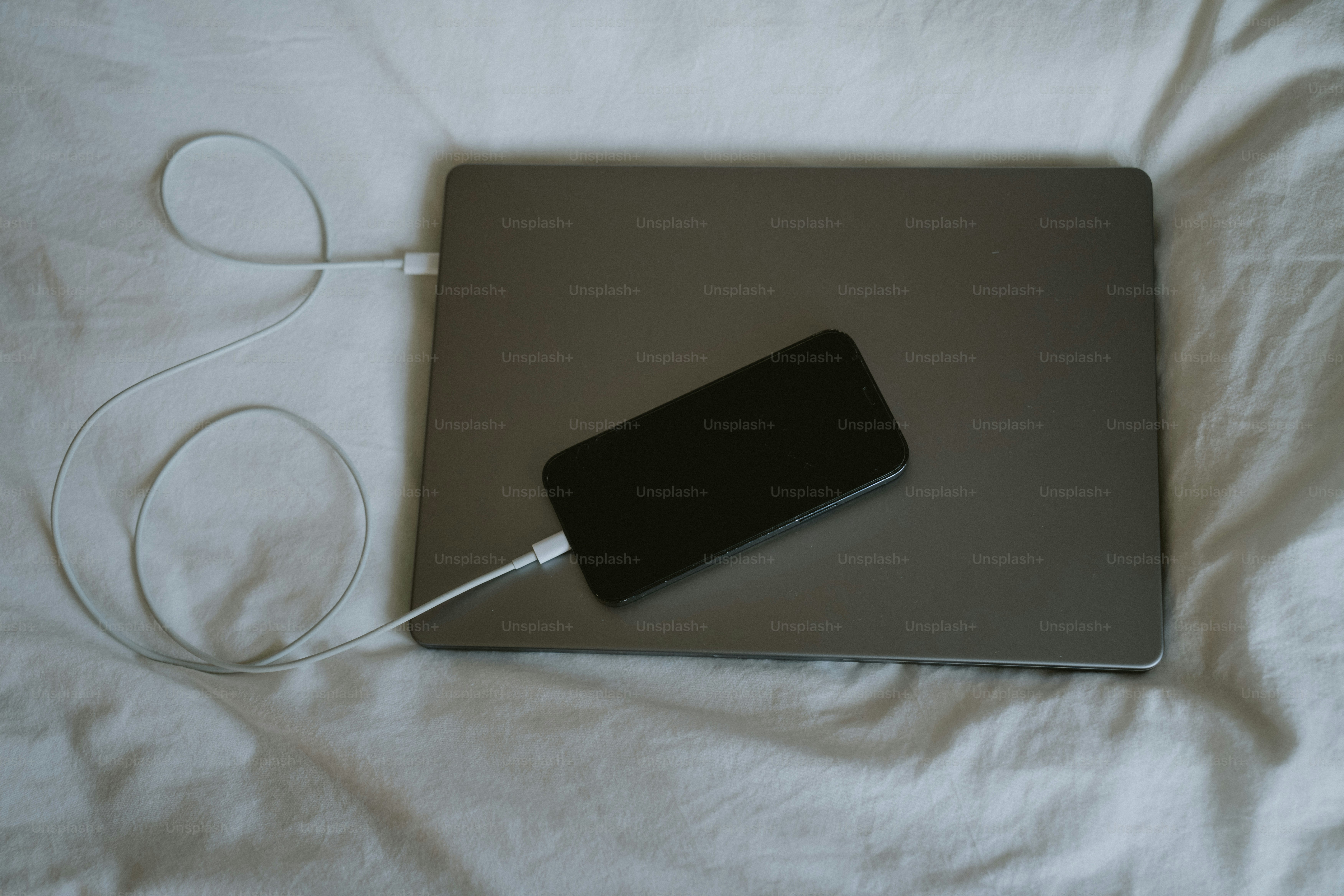 Ricarica dello smartphone su un portatile su un letto.