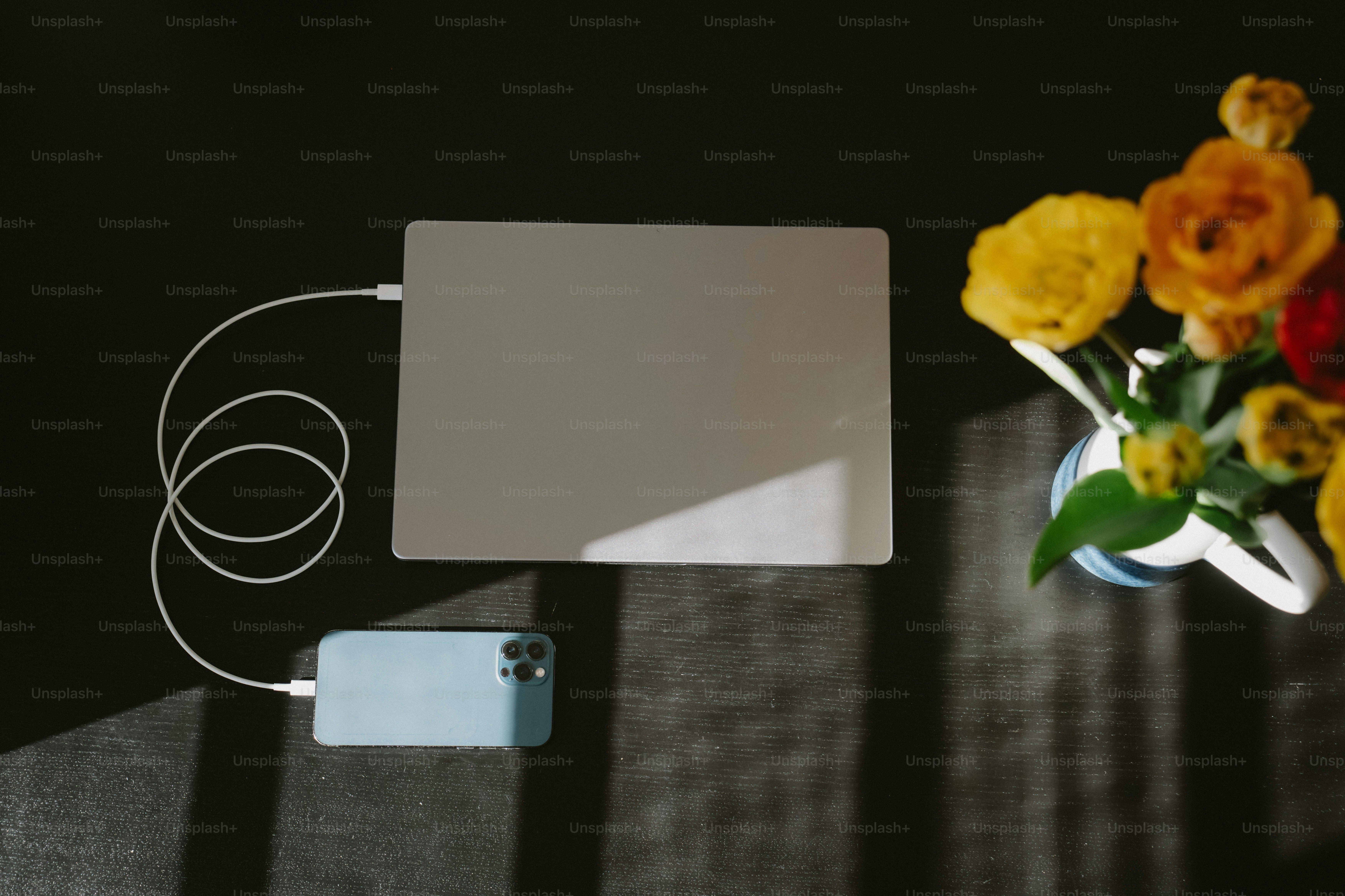 Laptop e telefono che si caricano con fiori vicino ai fiori