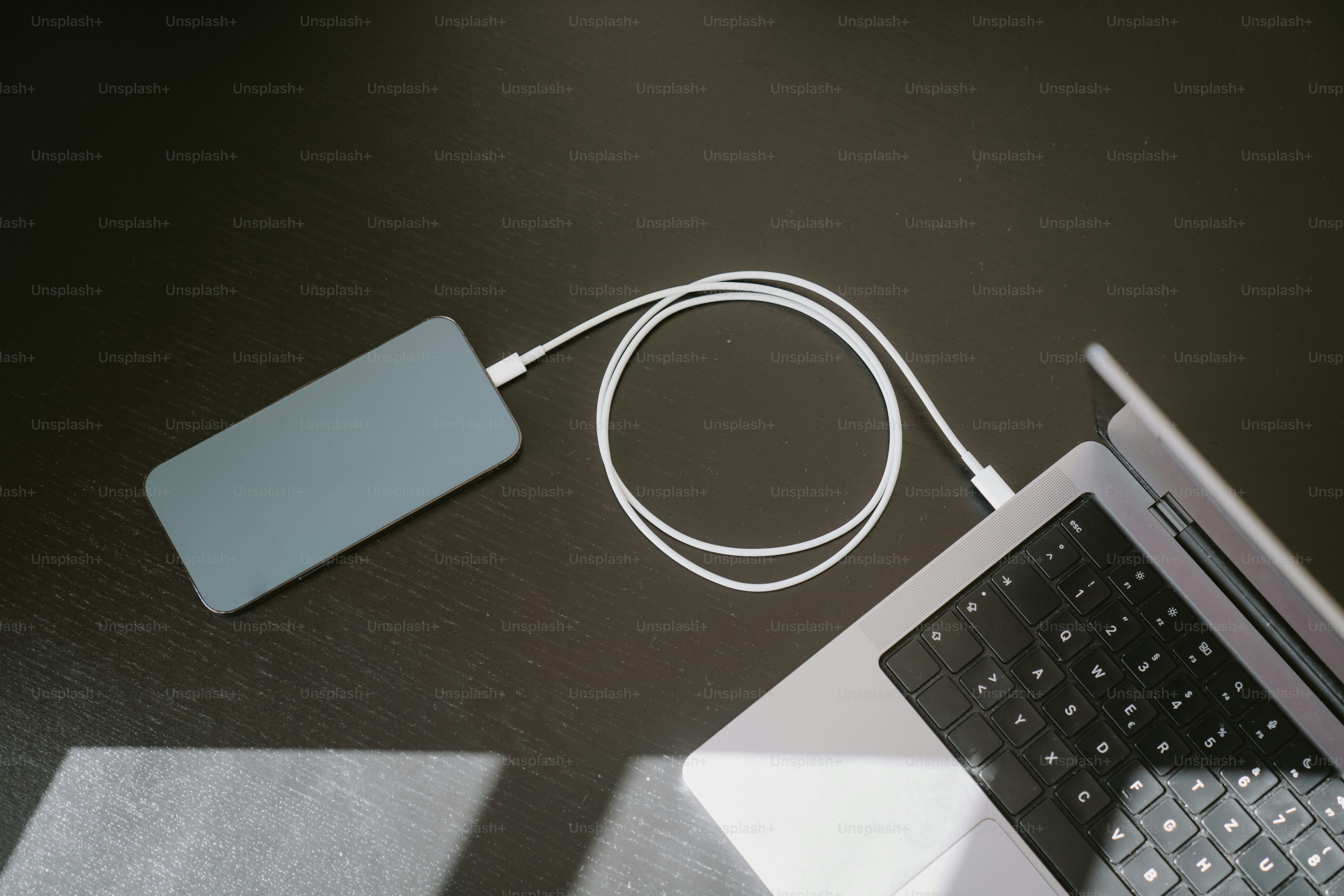 Uno smartphone si carica da un laptop con un cavo.