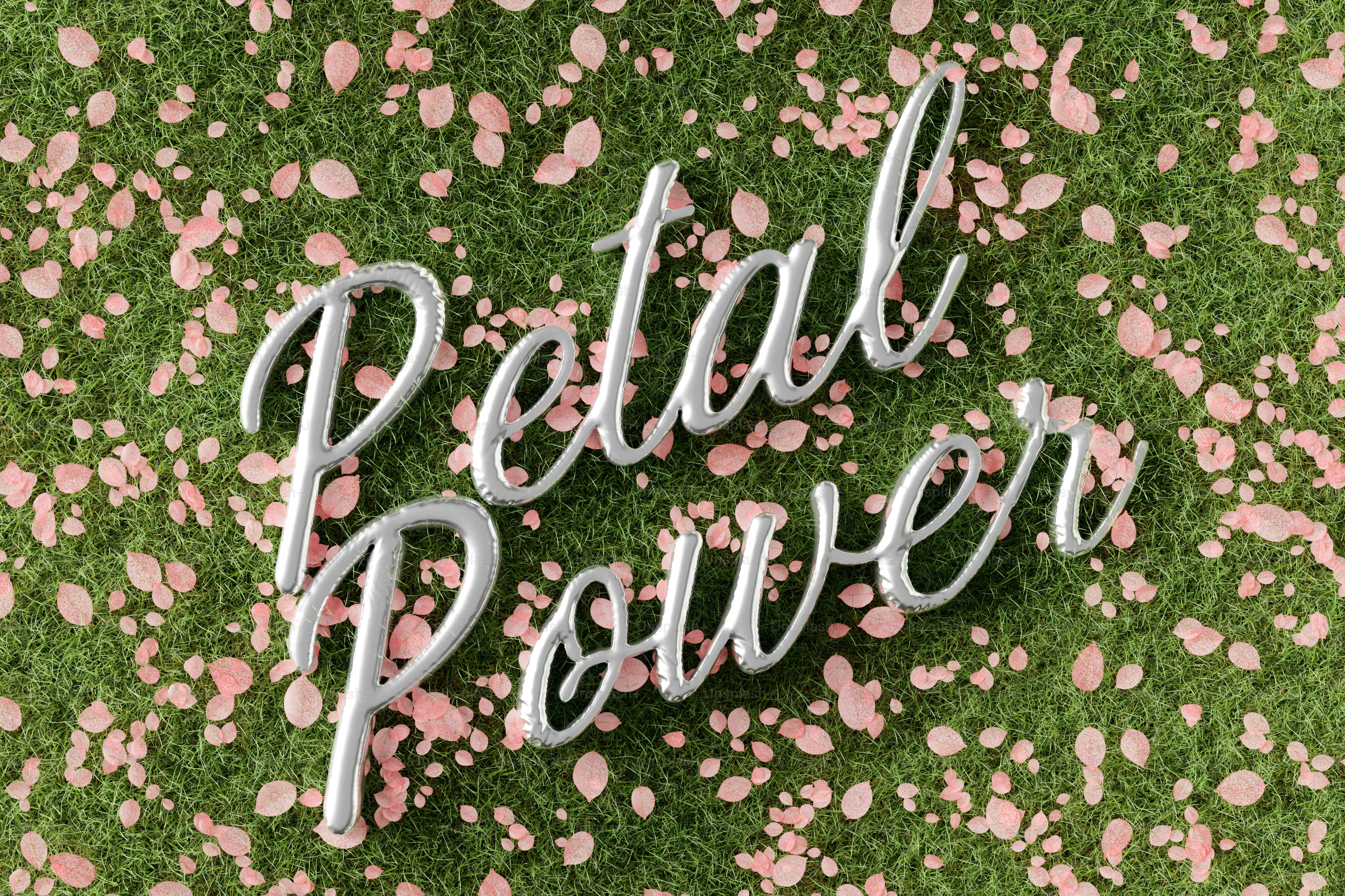 Silver text "petal power" on green grass with pink petals.