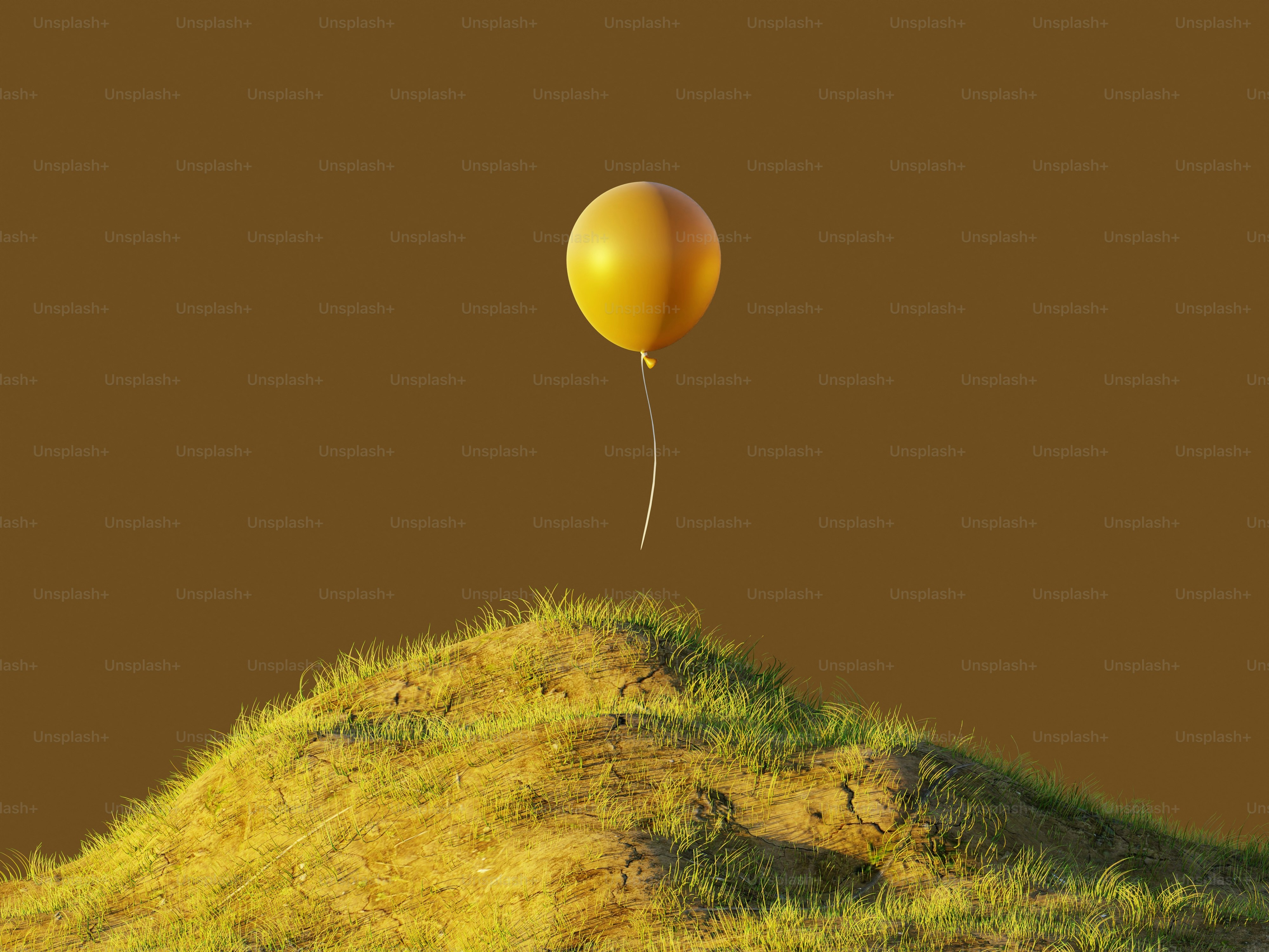 A single yellow balloon floats above a grassy hill.