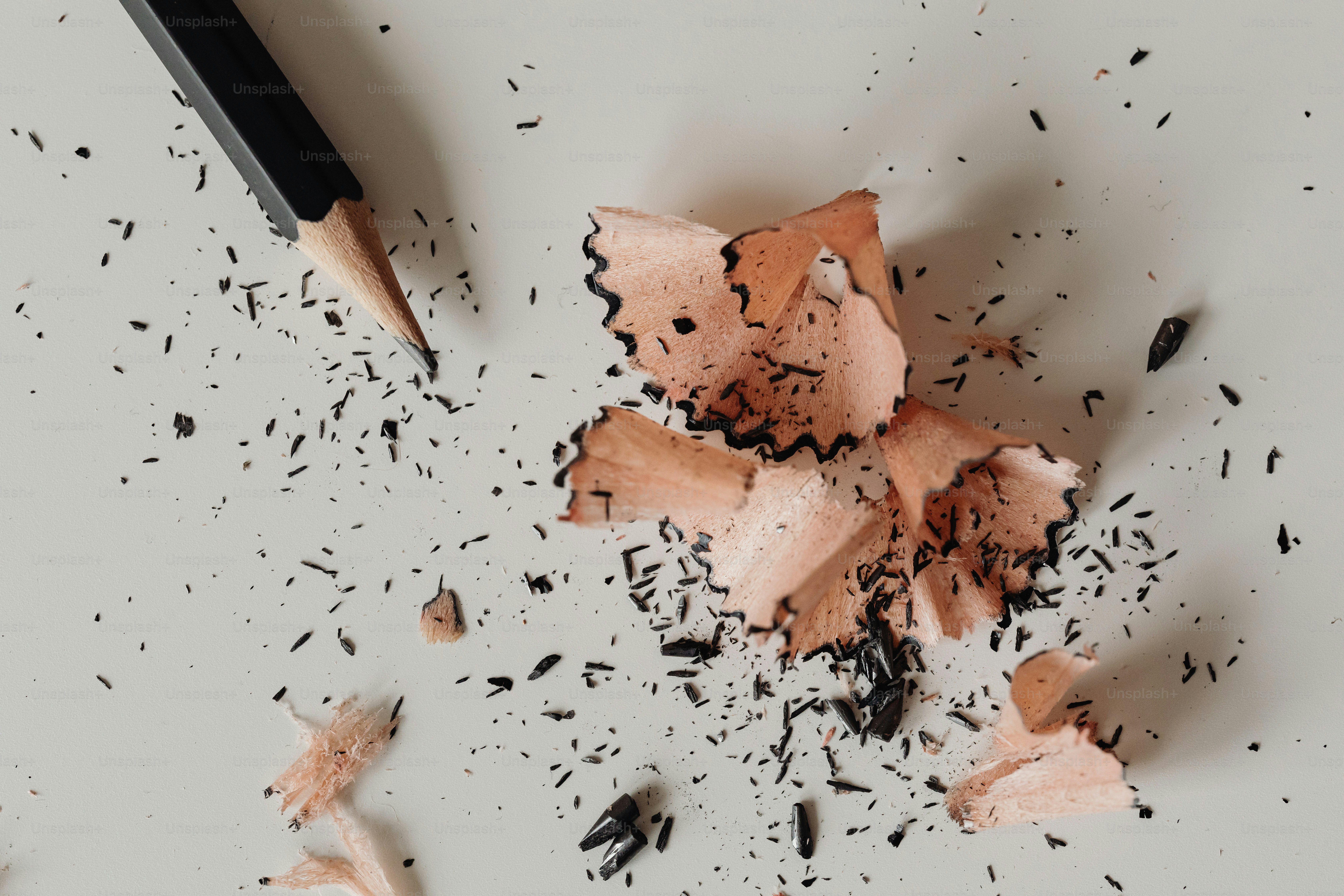 Pencil shavings and a pencil on a white surface
