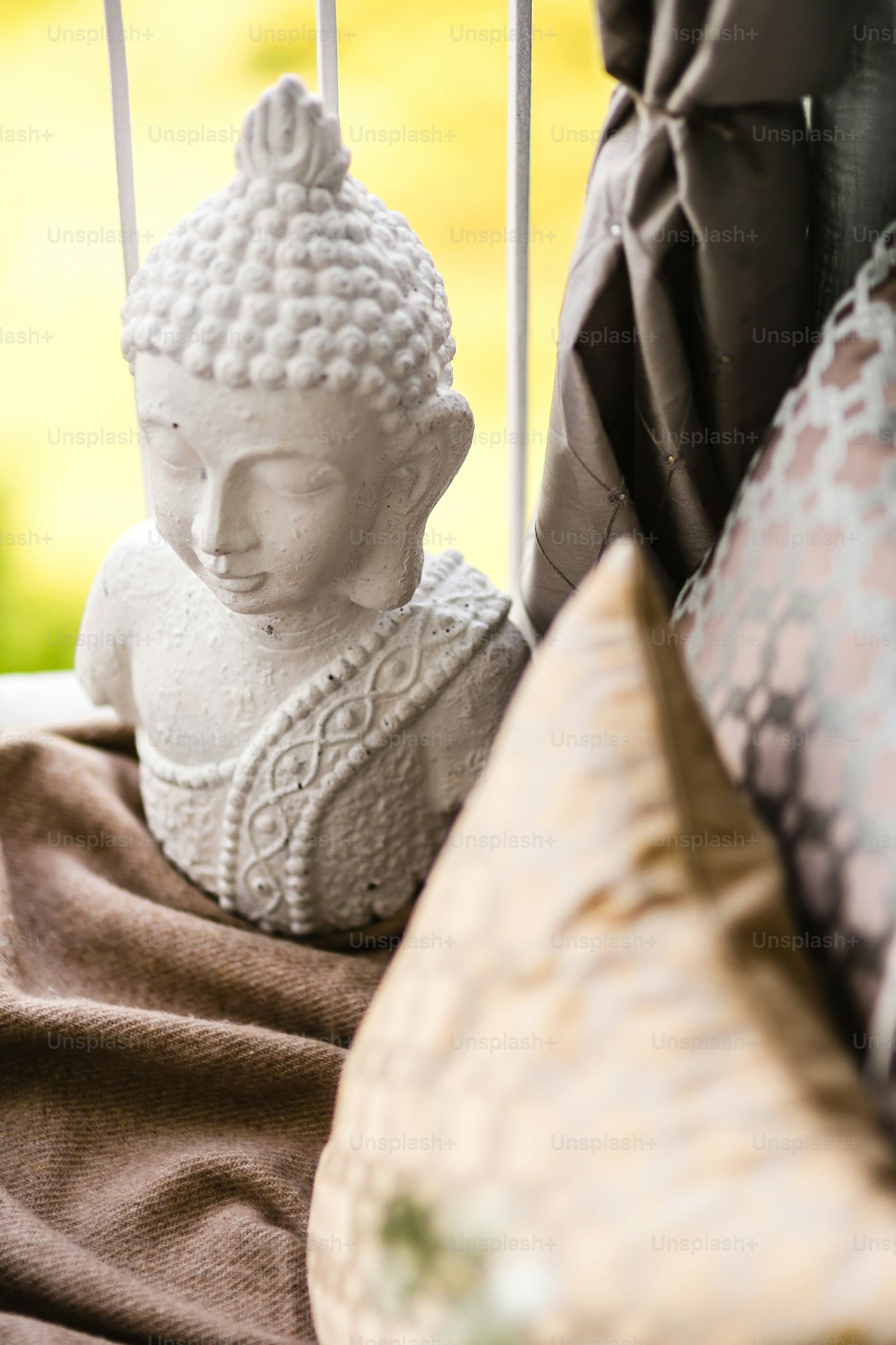 Eine kleine steinerne Buddha-Statue ruht in der Nähe von Kissen.