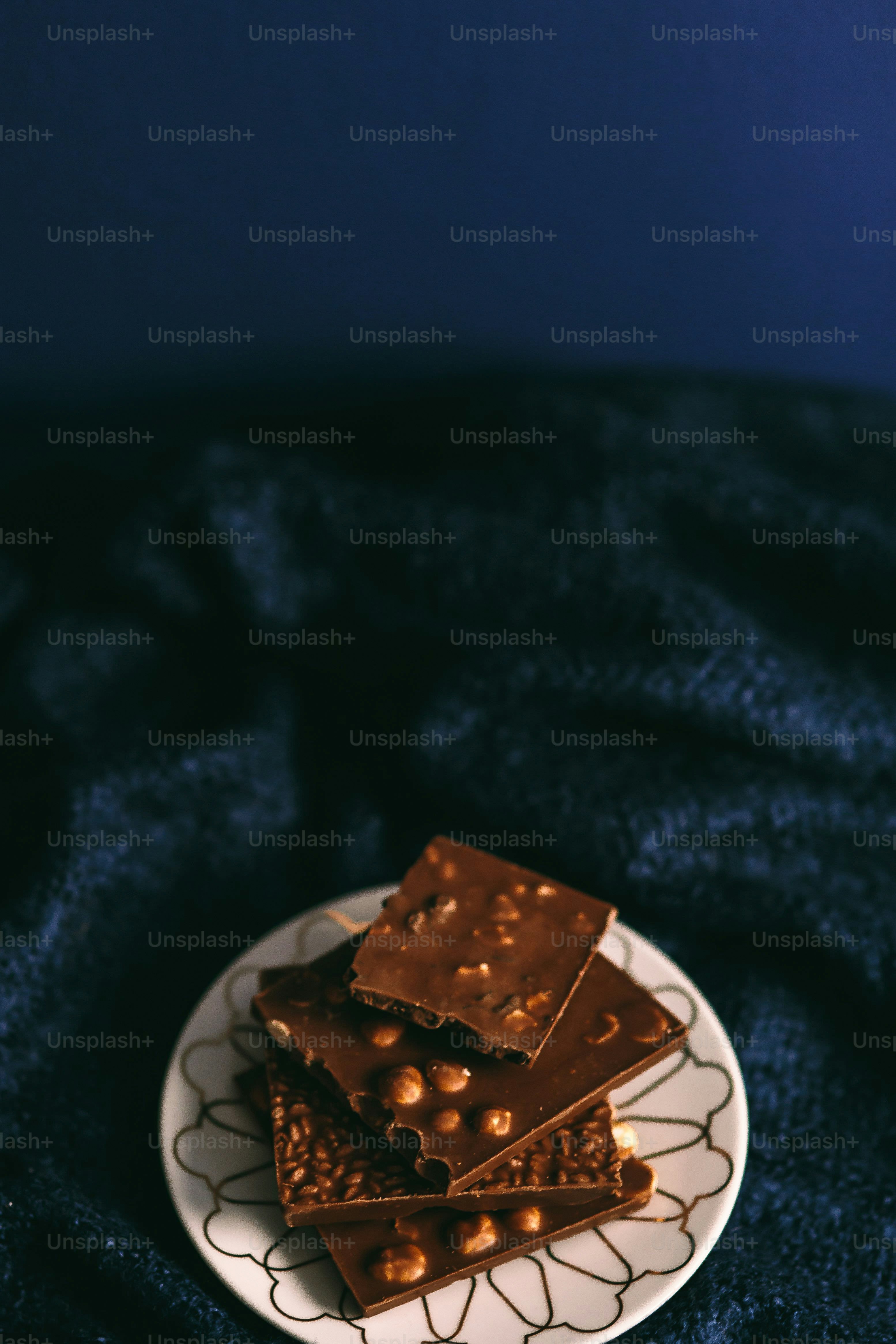 Stack of chocolate bars with nuts on a decorative plate. photo – Food ...
